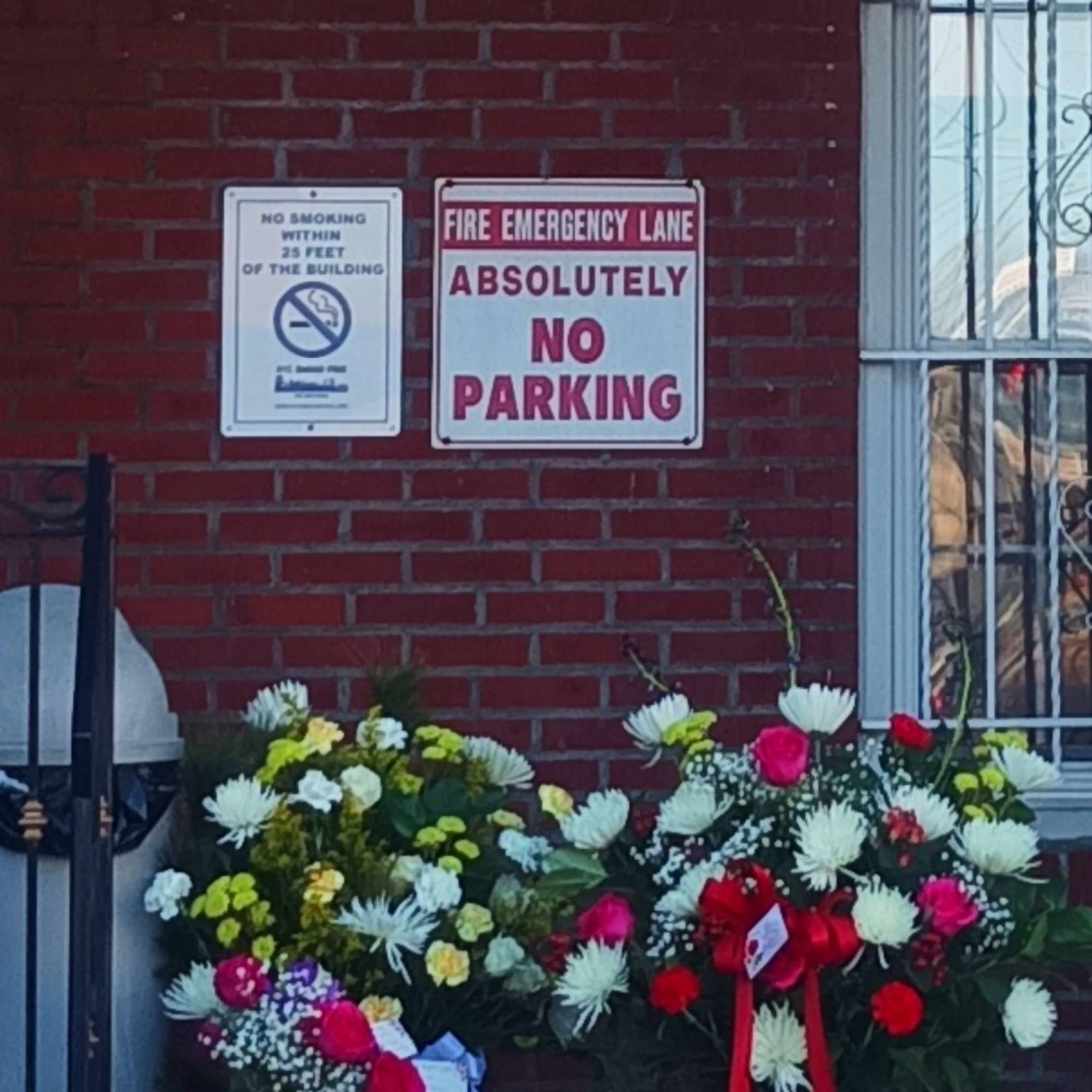Two floral sympathy arrangements with ribbons on a brick ledge
