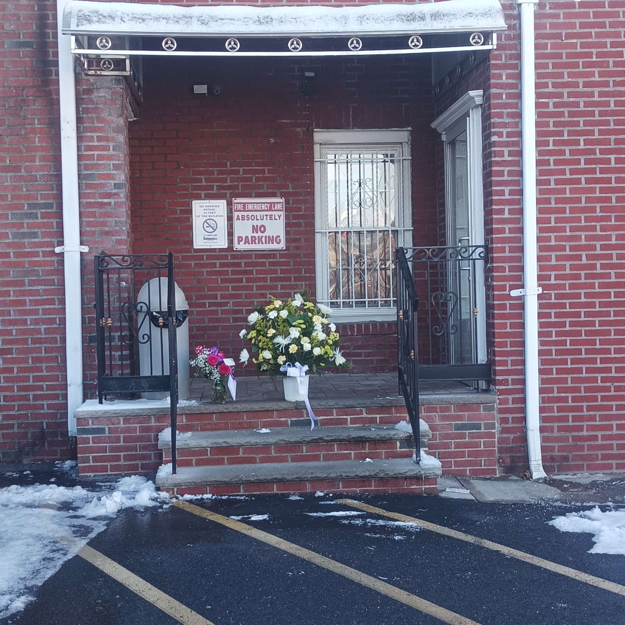 Two floral tributes sit on a brick porch outside a building