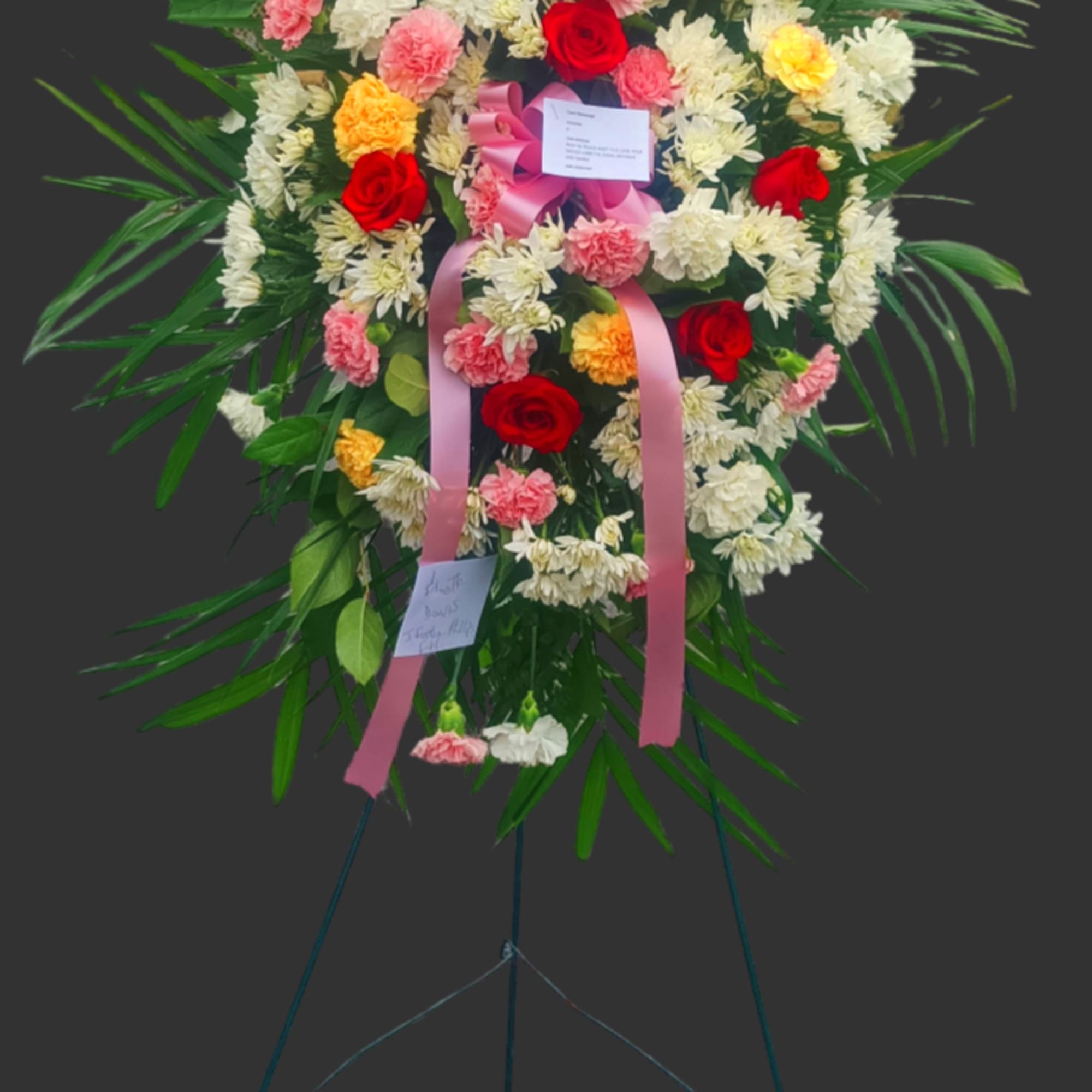 Standing floral wreath with red, pink, white, and yellow blooms on an easel