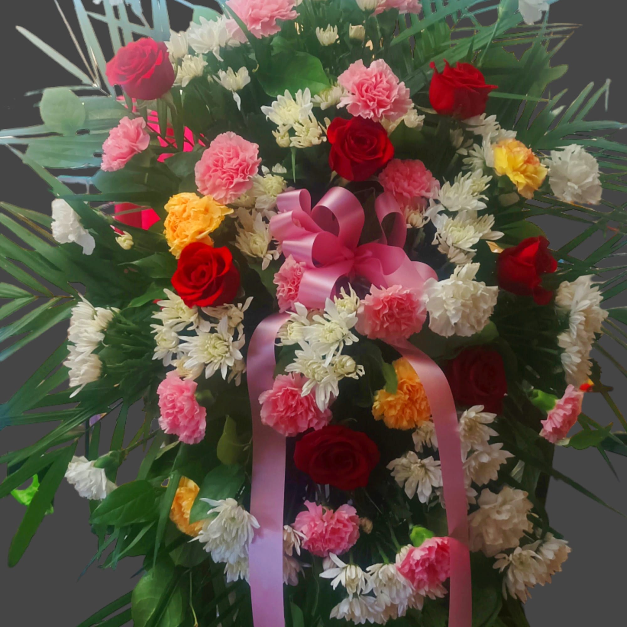 Large standing floral spray with roses, carnations, and pink ribbon
