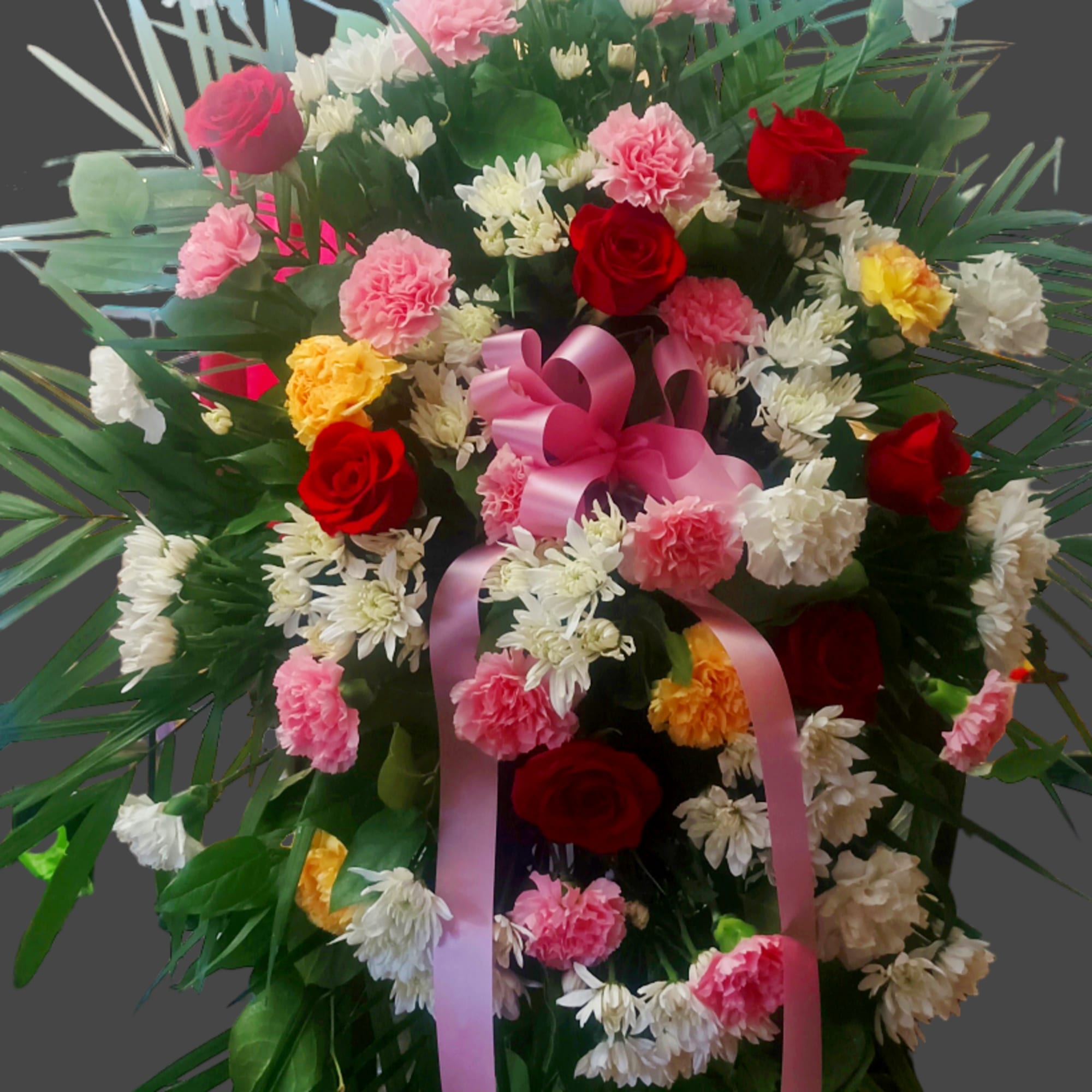 Standing floral spray with red and pink roses, carnations, and white daisies