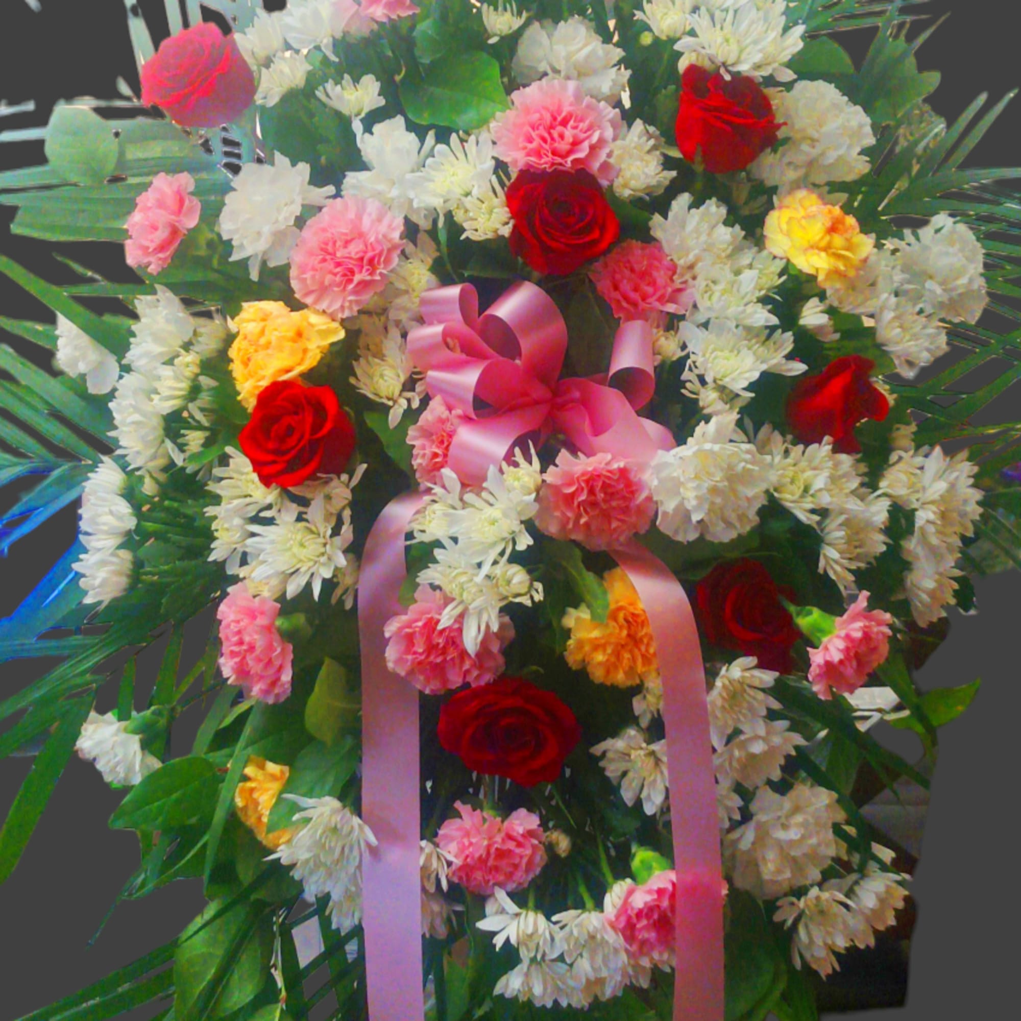 Large standing floral spray with red roses, pink carnations, and white daisies