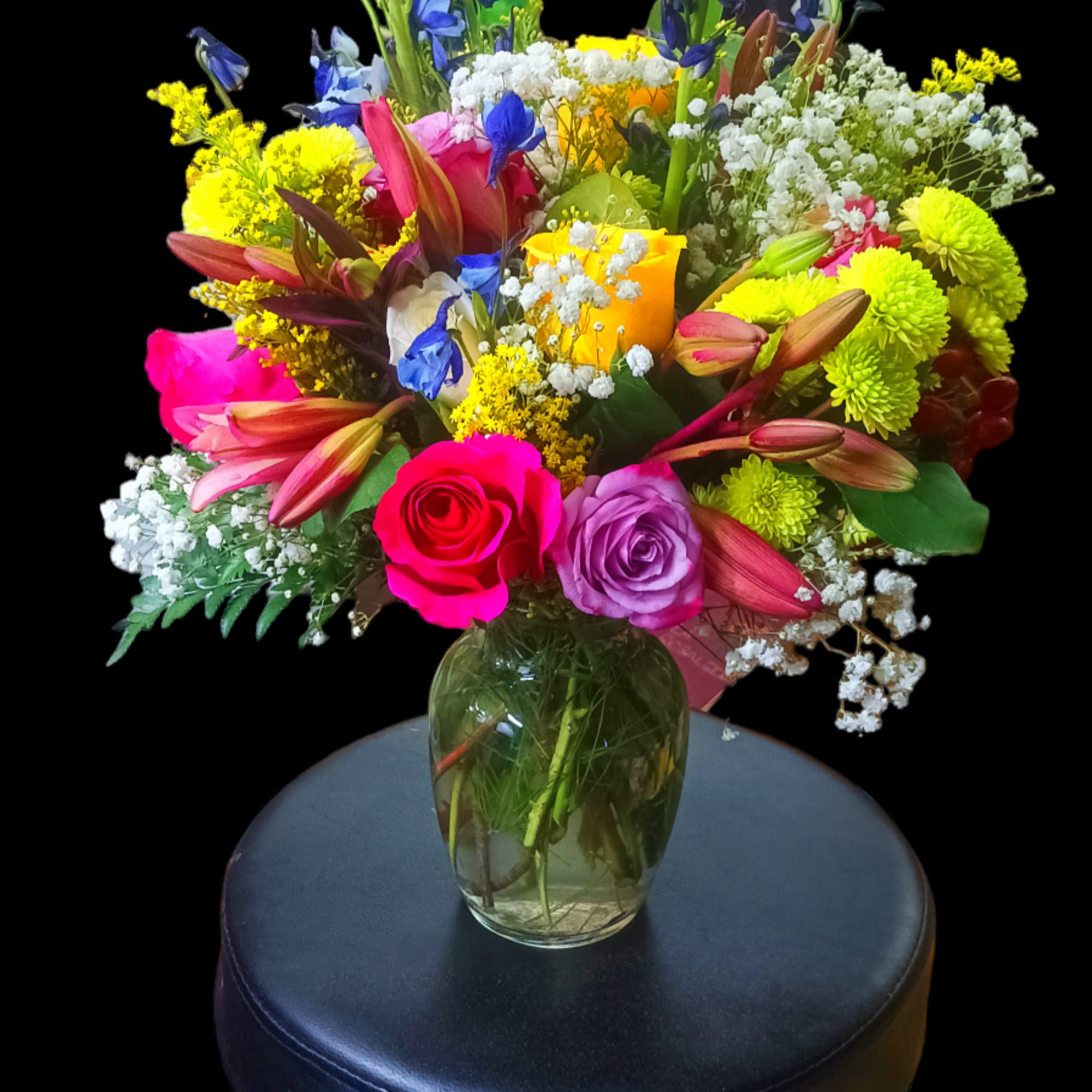 Colorful mixed bouquet in a glass vase on a stool