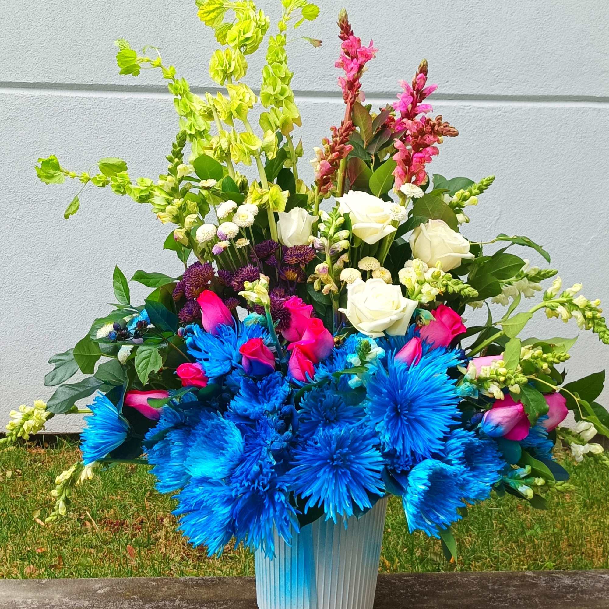 Bright mixed bouquet in a blue vase with blue, pink, white, and green flowers