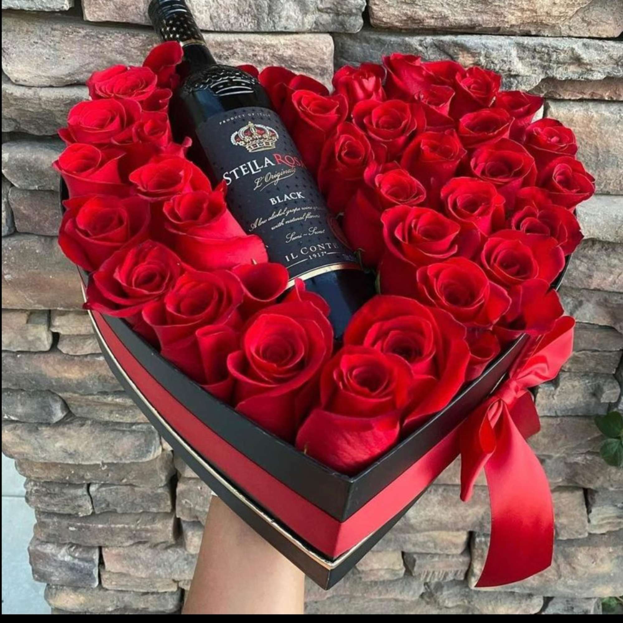Heart-shaped box of red roses with a wine bottle in the center