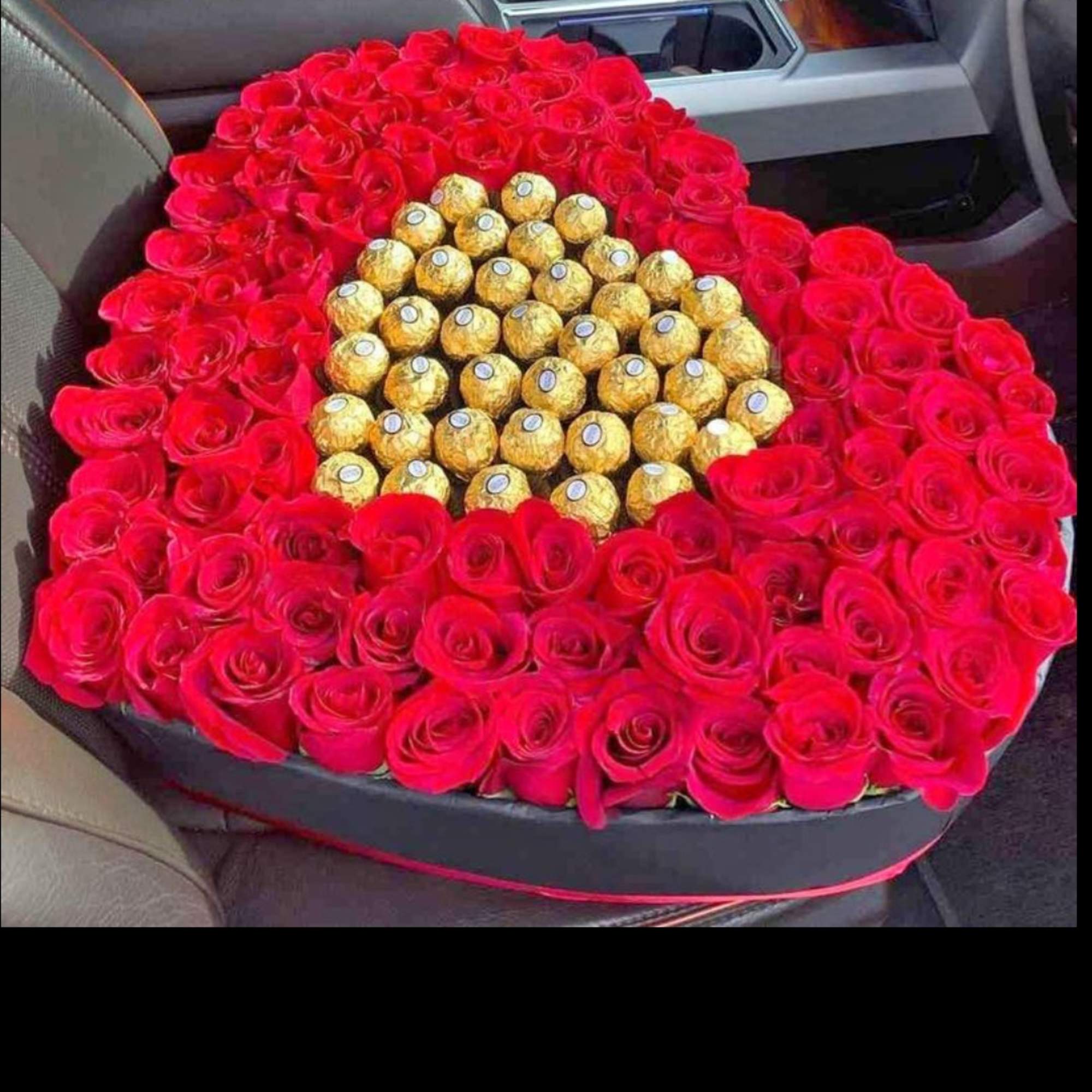 Heart-shaped box of red roses with gold-wrapped chocolates in the center