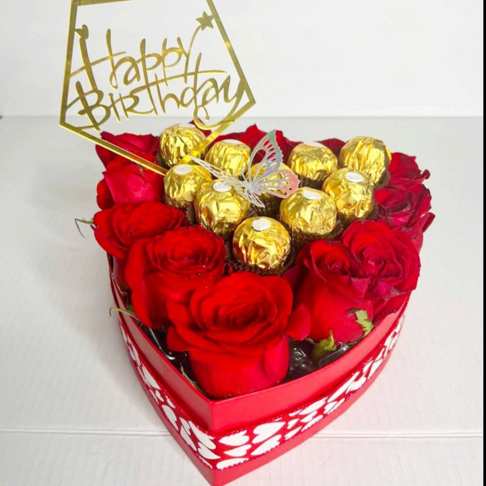 Heart-shaped box of red roses with gold-wrapped chocolates and a birthday topper