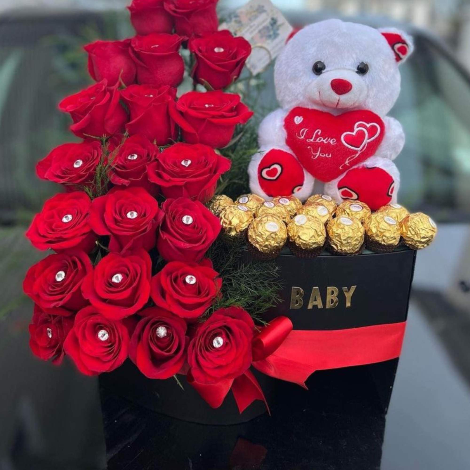 Red roses in a black box with a teddy bear and chocolates