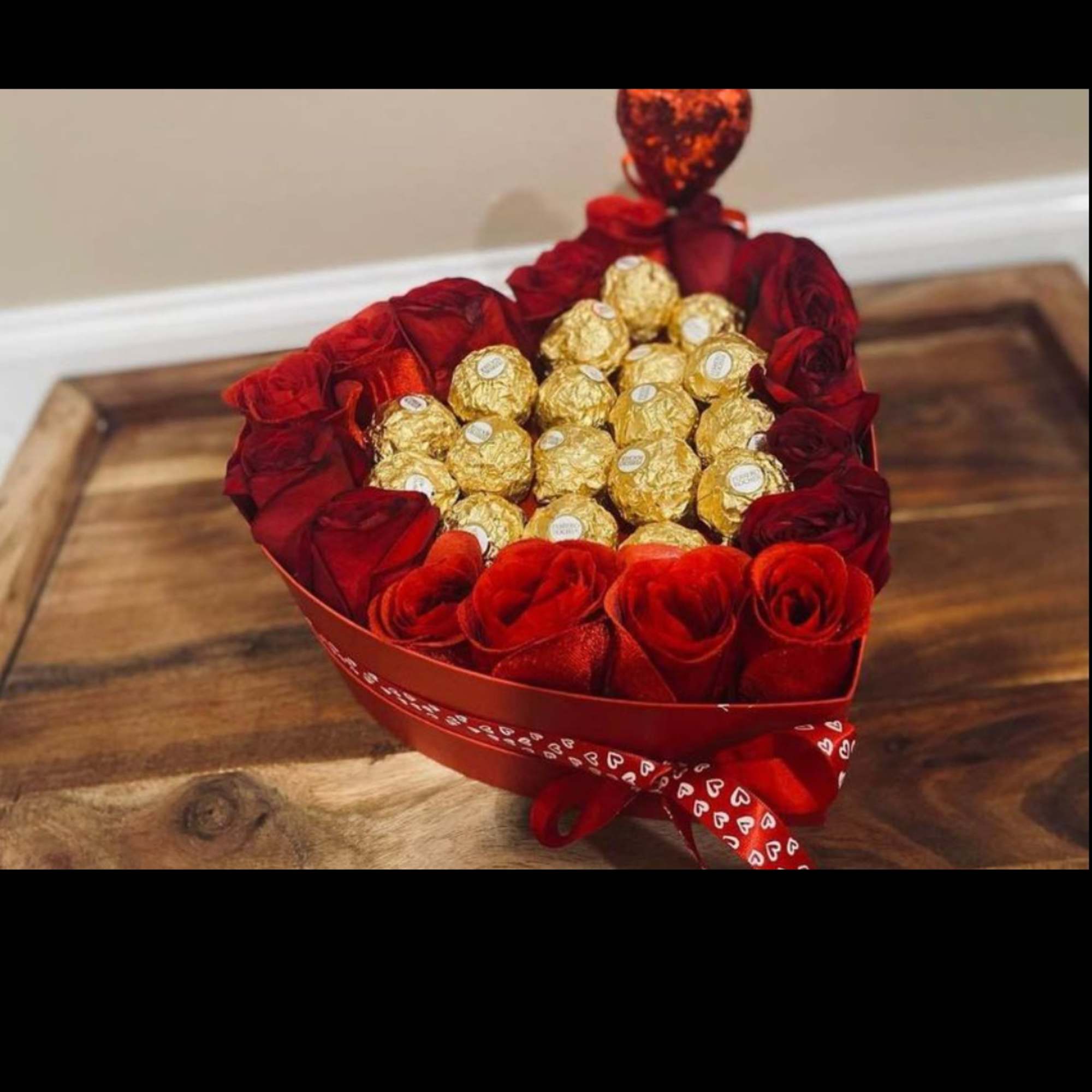 Heart-shaped box of red roses filled with gold-wrapped chocolates