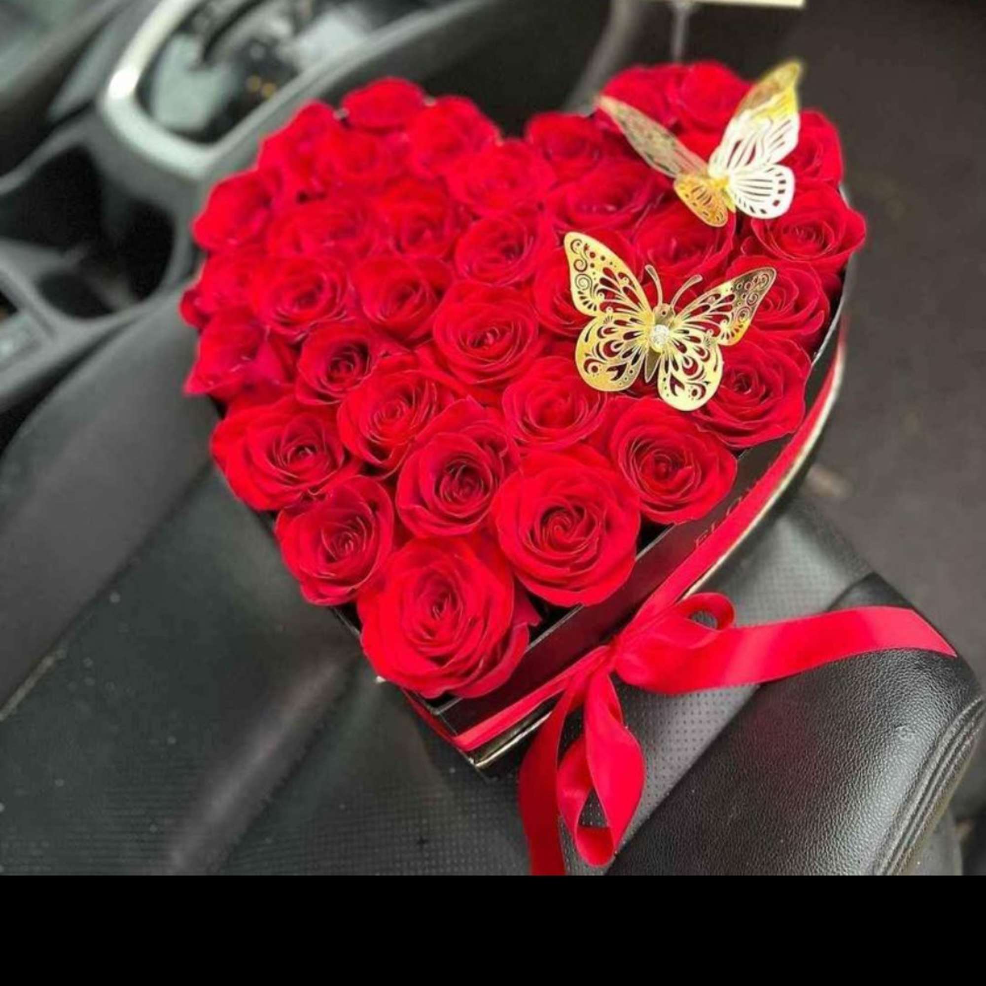 Heart-shaped box of red roses with butterfly decorations and a red ribbon