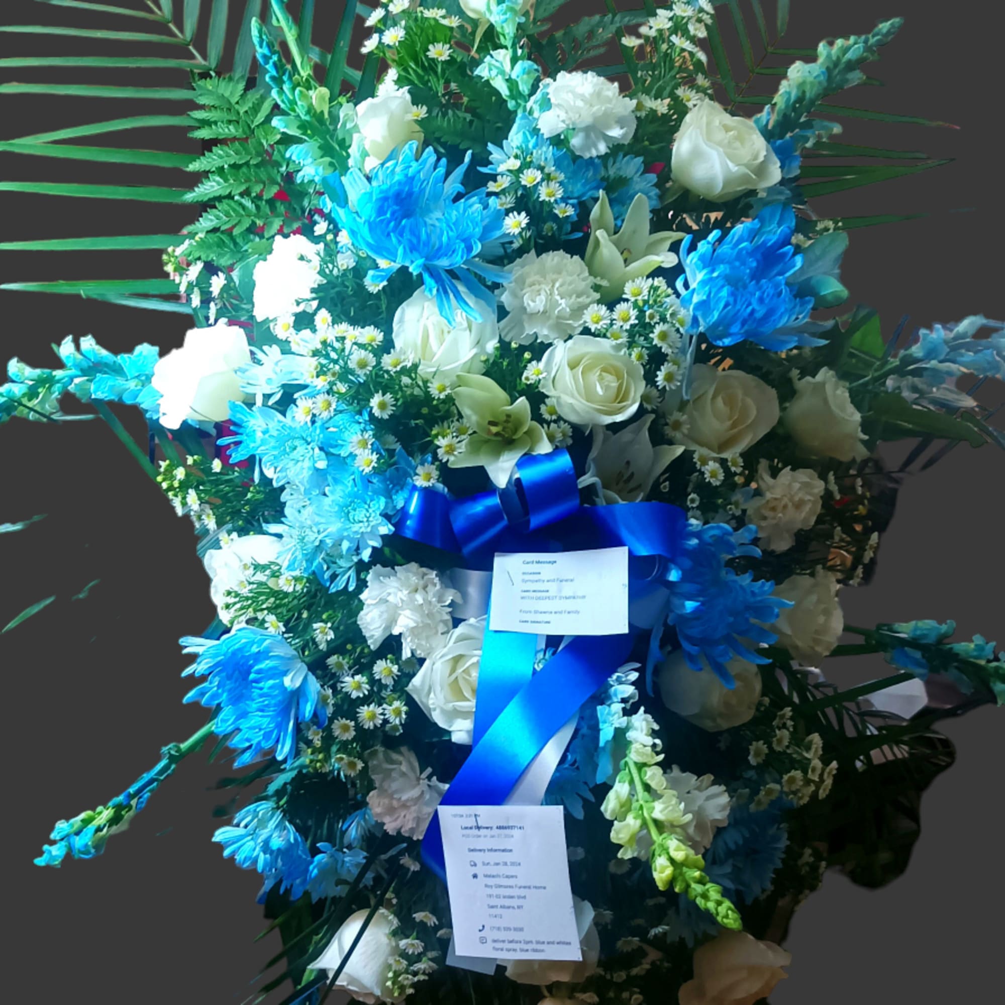 Tall blue and white floral standing spray on an easel with ribbon