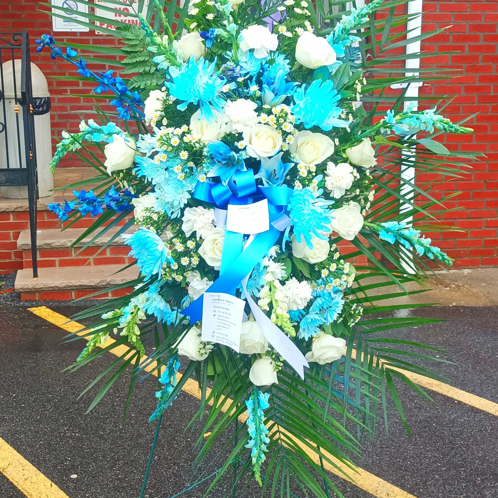 Large standing floral spray with white roses and blue flowers on an easel