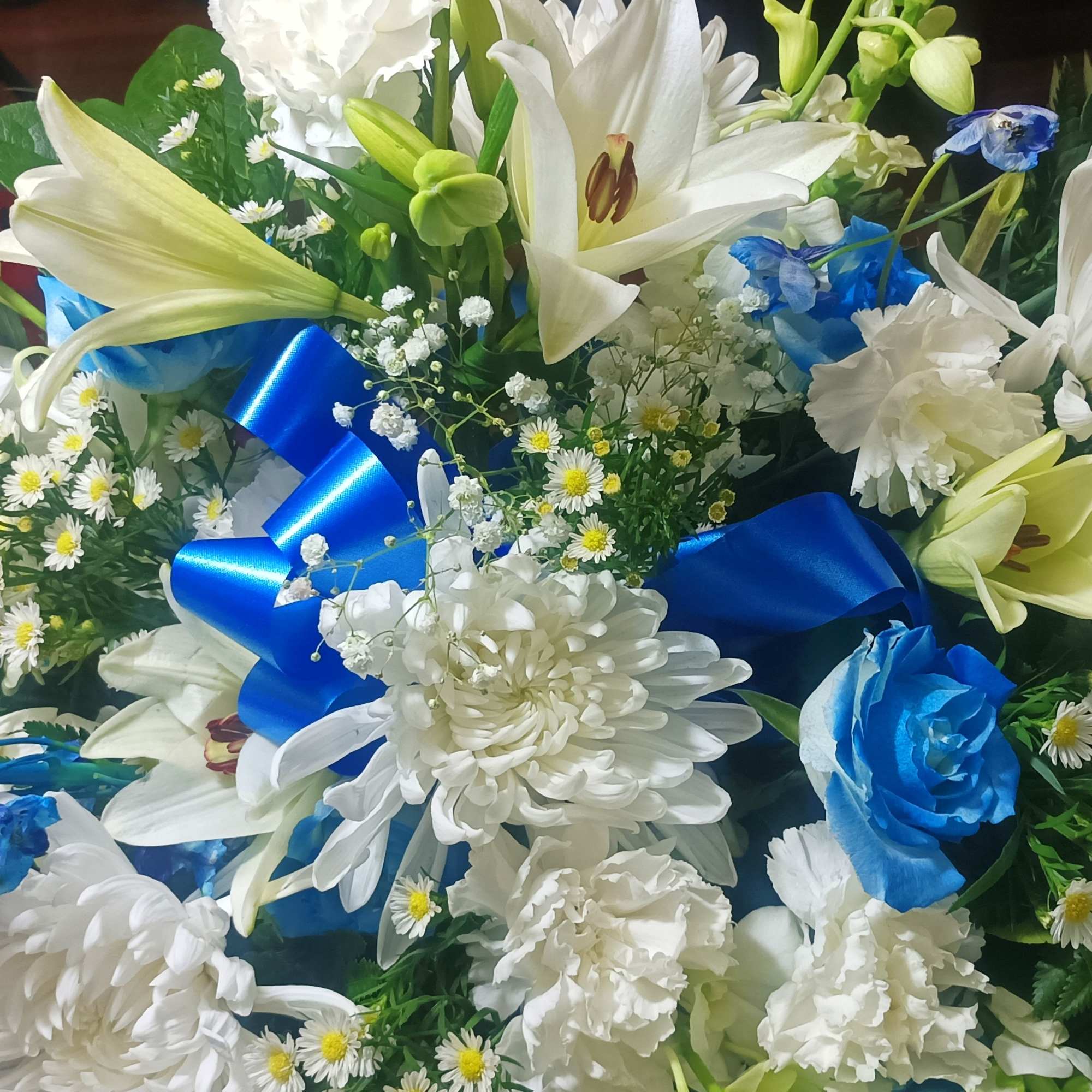 White and blue floral arrangement with lilies, daisies, and roses