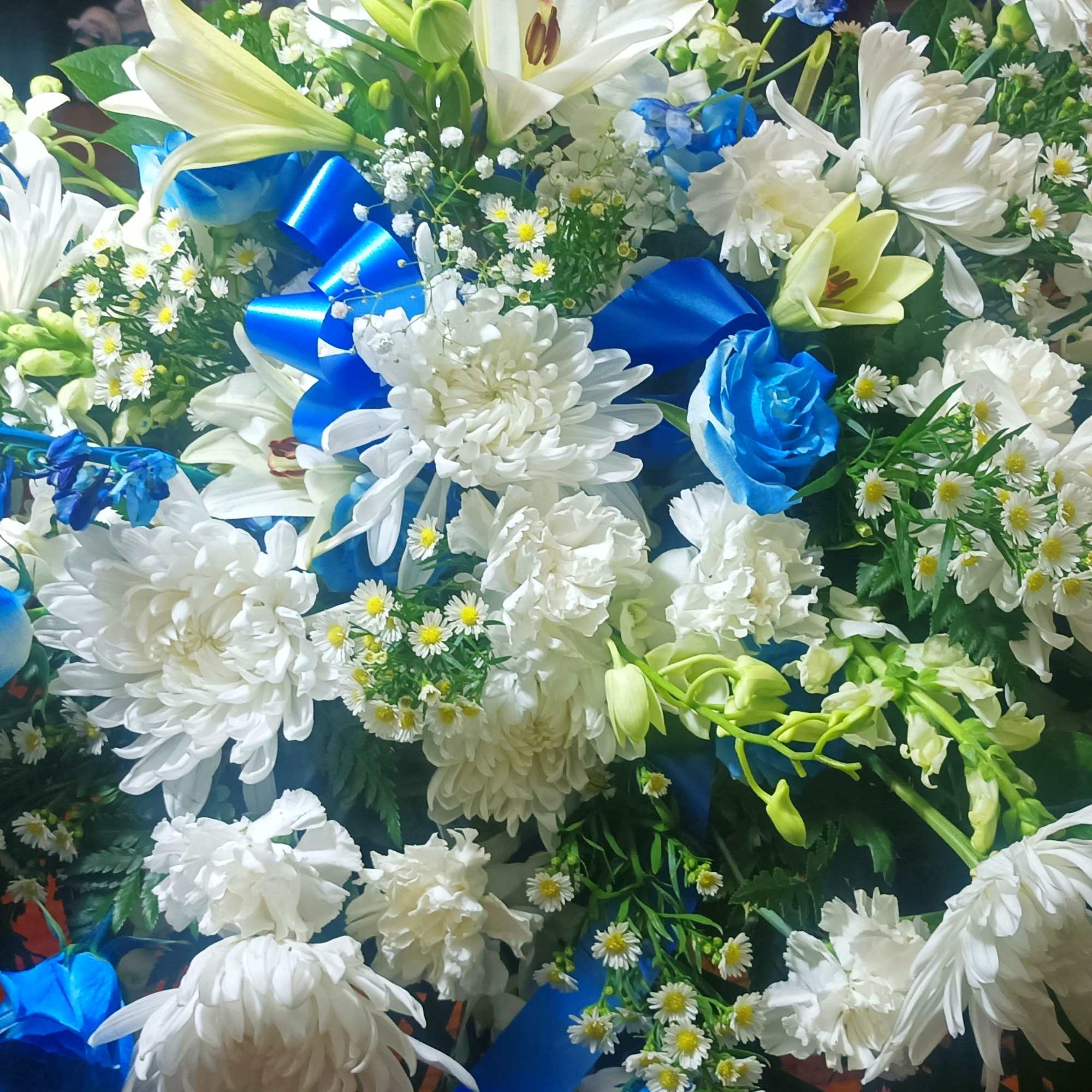 Large white and blue floral arrangement with ribbons