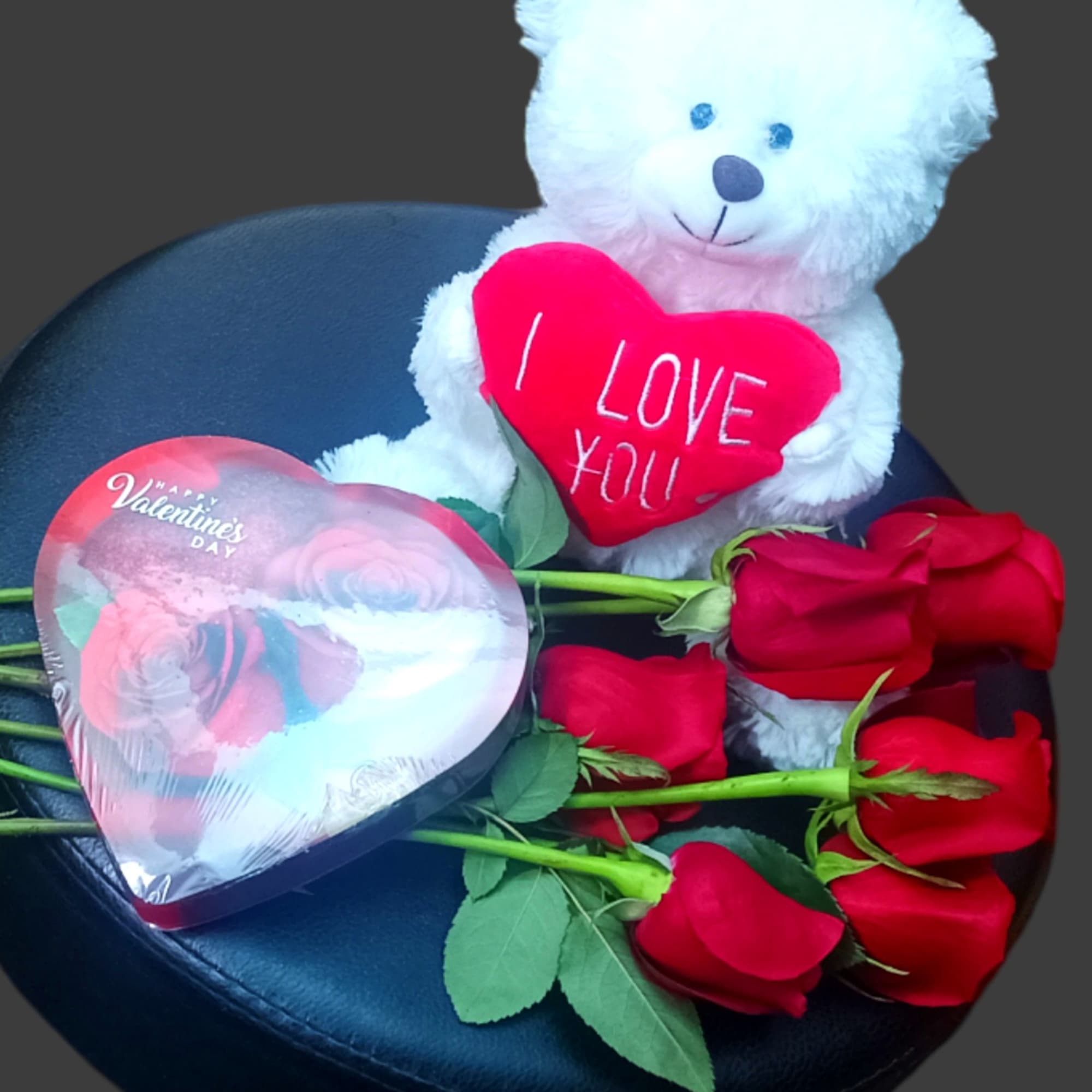 White teddy bear holding a red heart with red roses and a heart-shaped box