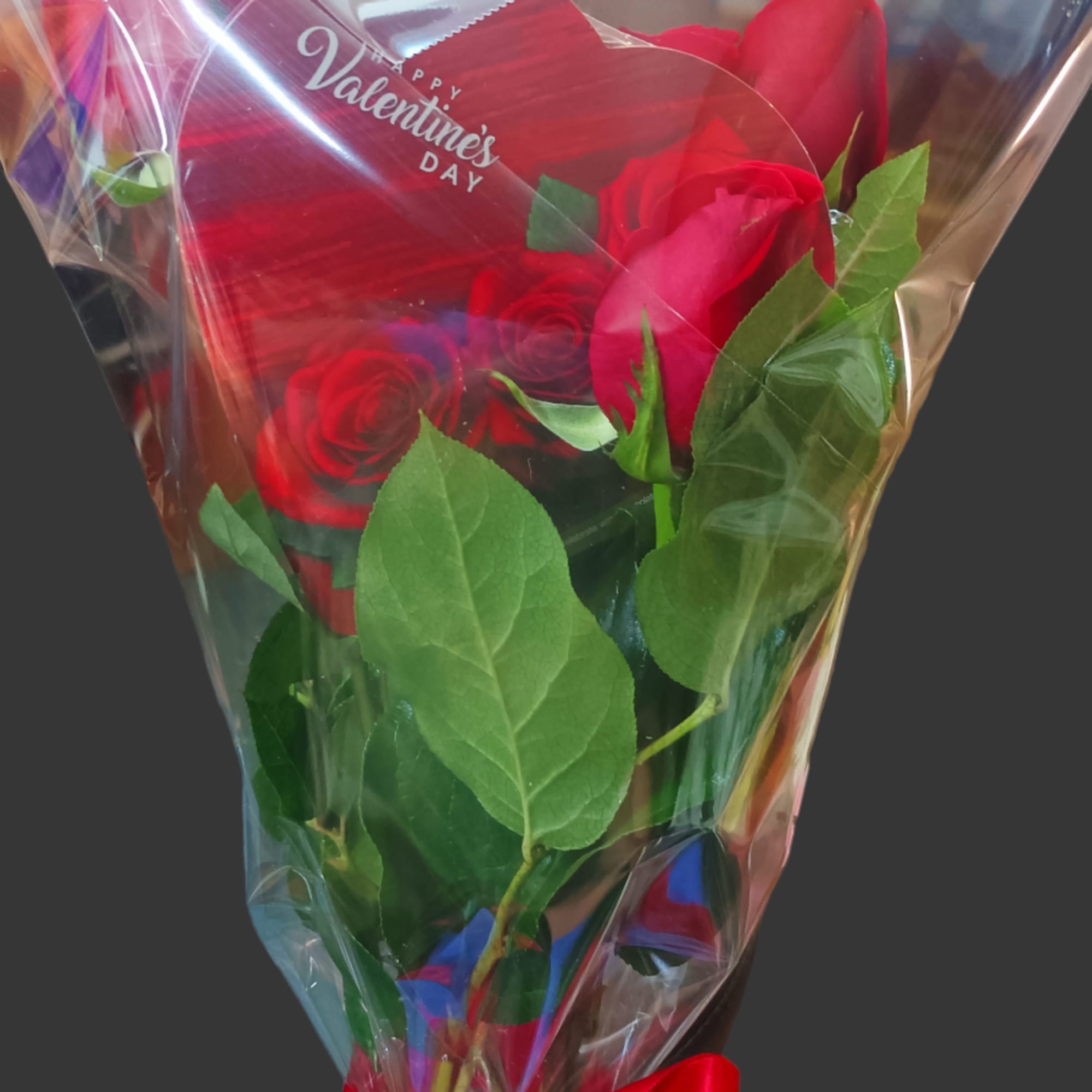 Wrapped bouquet of red roses with a red ribbon