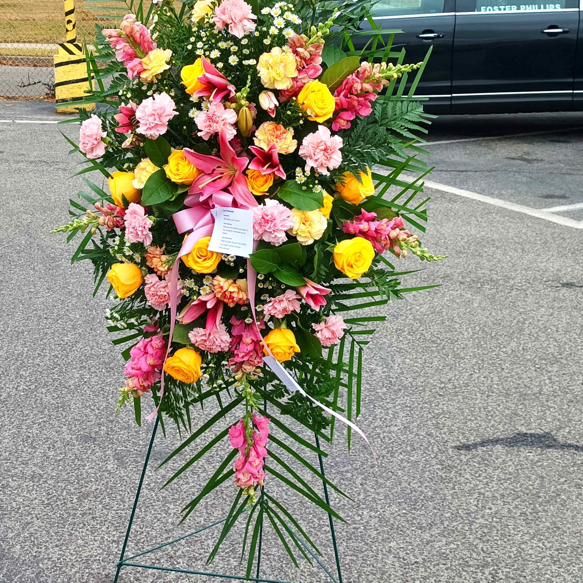Standing floral spray with pink, yellow, and white flowers on an easel