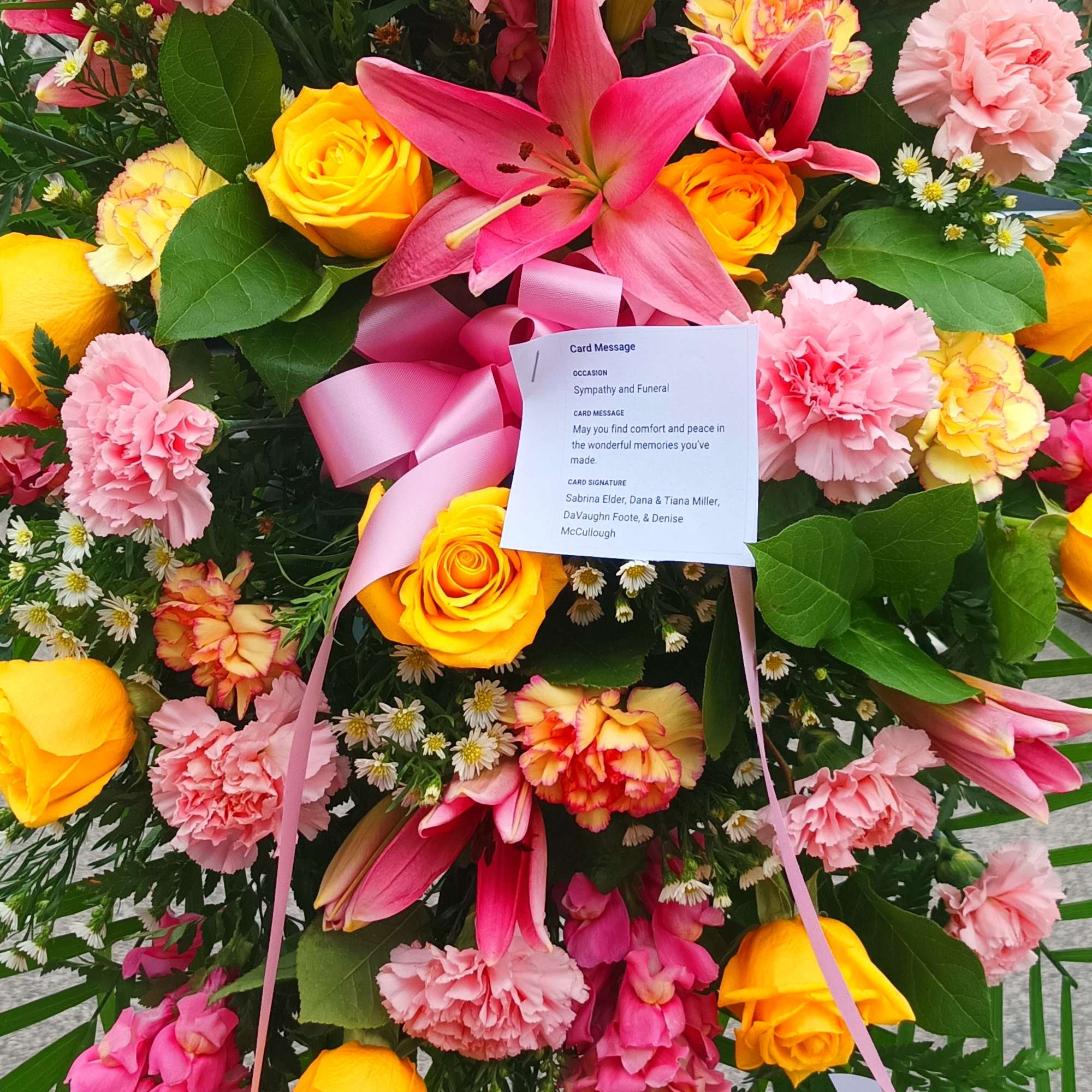 Large sympathy spray with pink, yellow, and red flowers on a stand