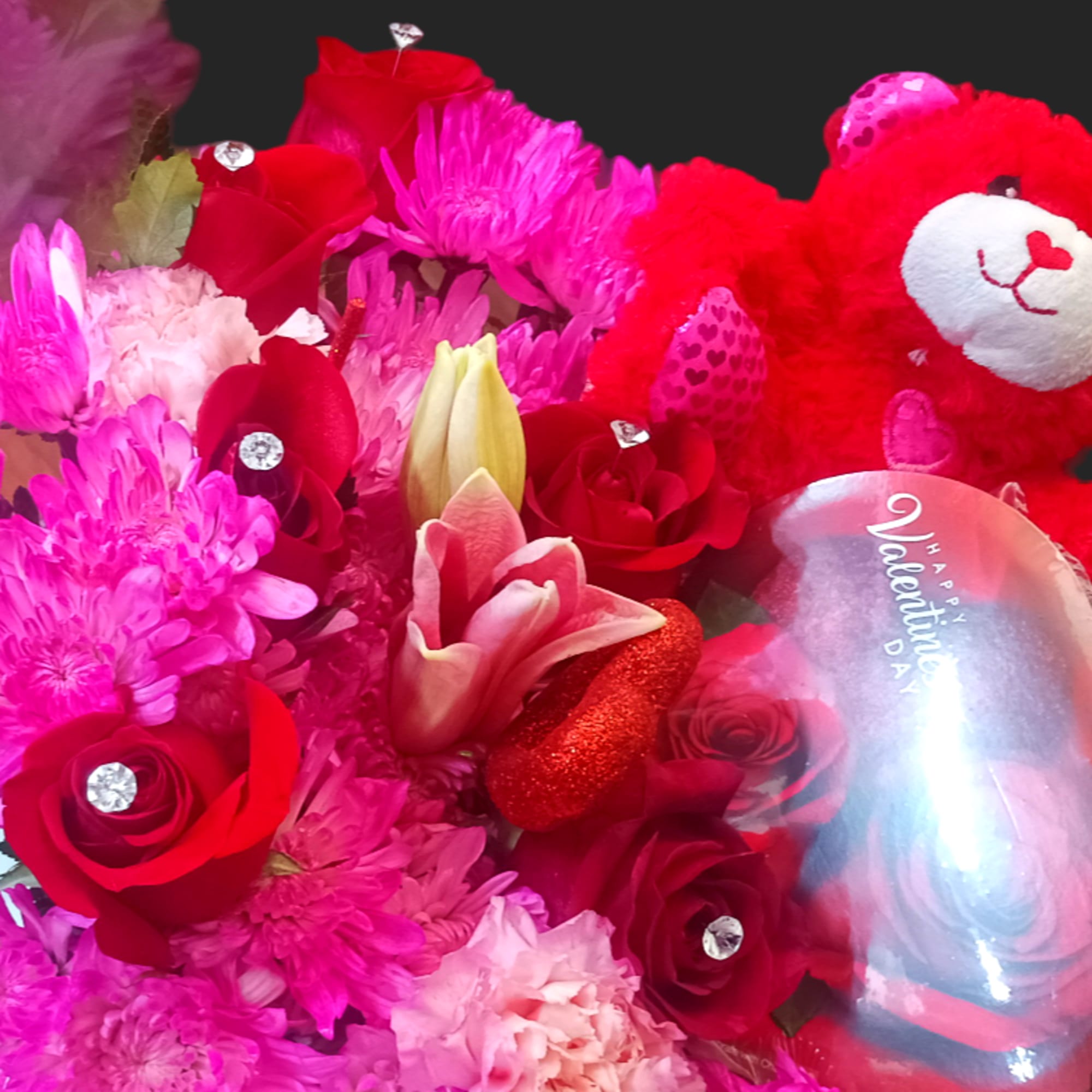 Bouquet of red and pink flowers with a red teddy bear and heart-shaped balloon