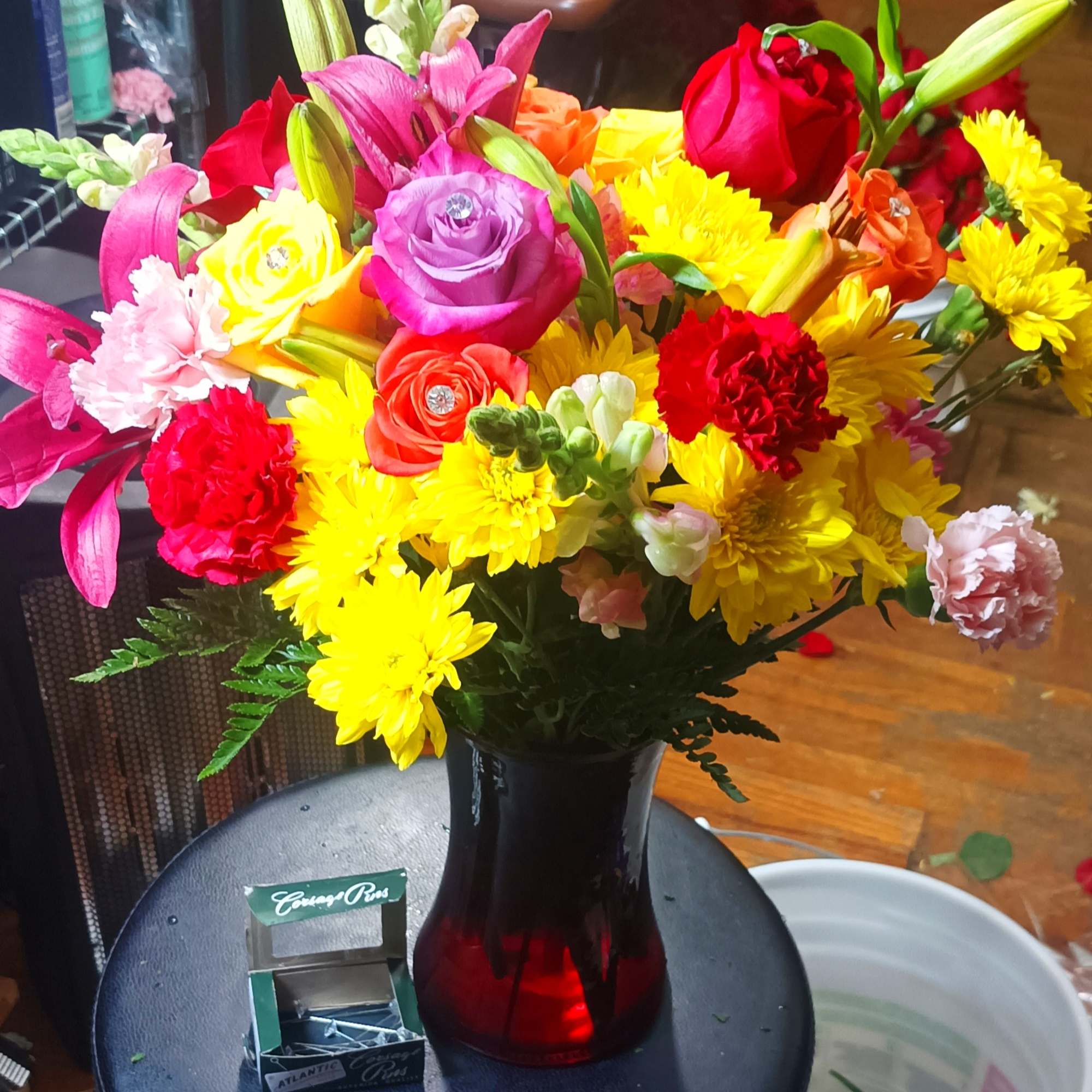 Colorful bouquet of roses, lilies, and chrysanthemums in a red vase