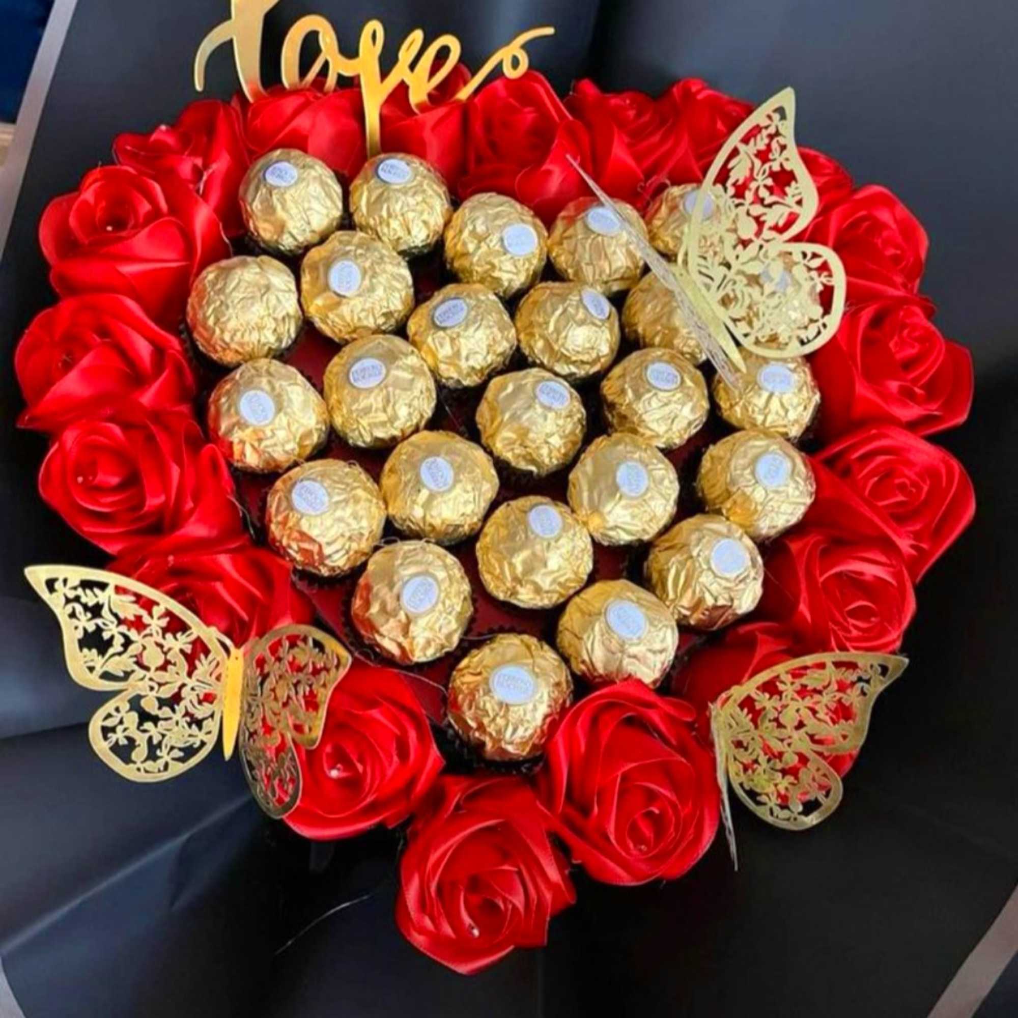 Heart-shaped arrangement of red roses and gold-wrapped chocolates