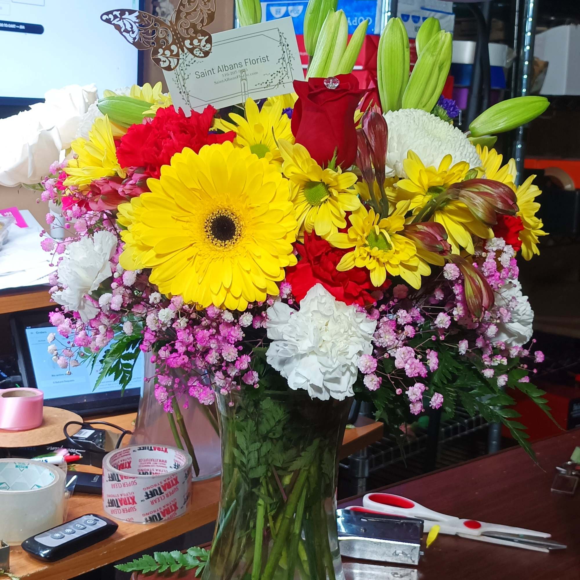 Mixed bouquet in a clear glass vase with yellow, red, and white flowers