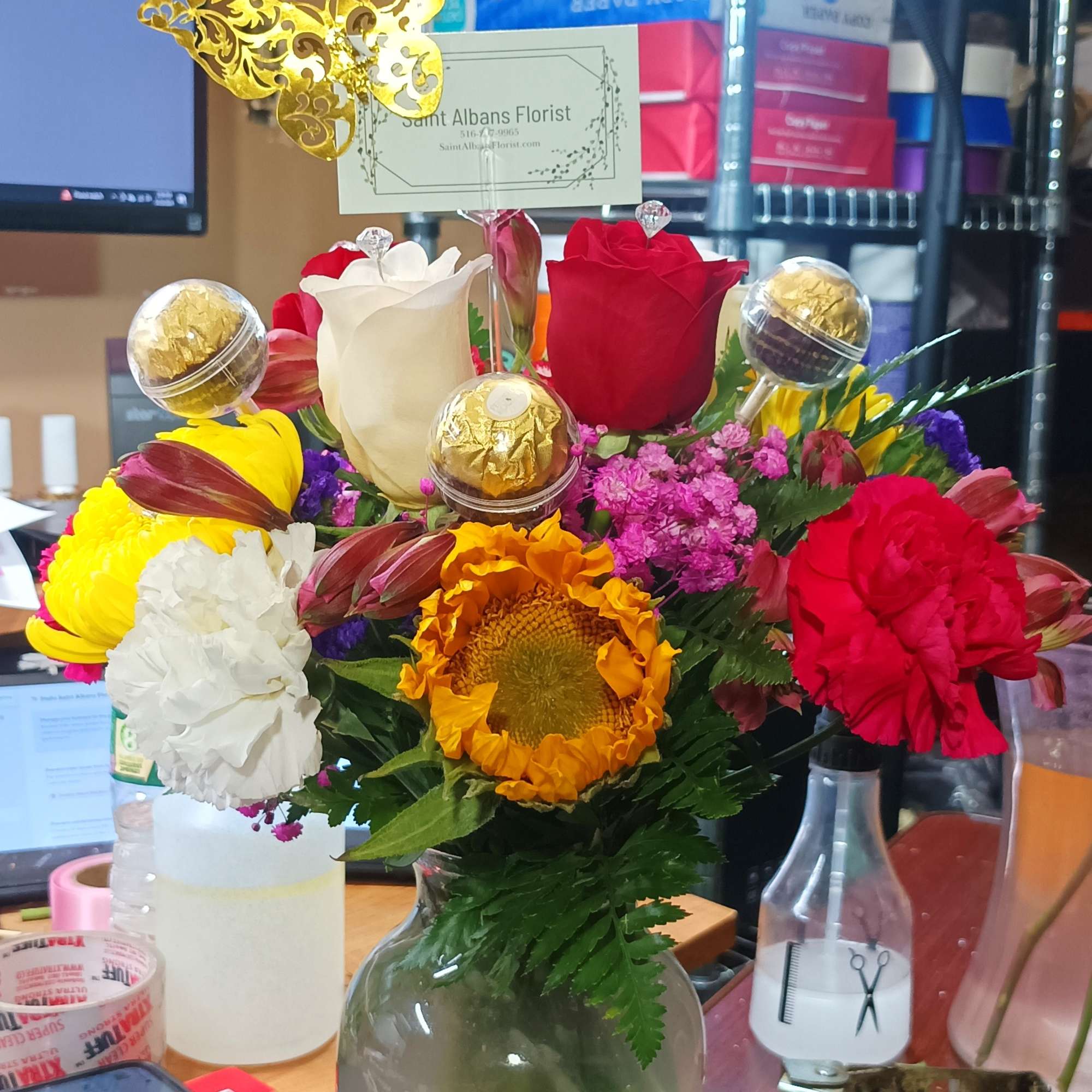 Mixed bouquet in a glass vase with roses, carnations, and a sunflower