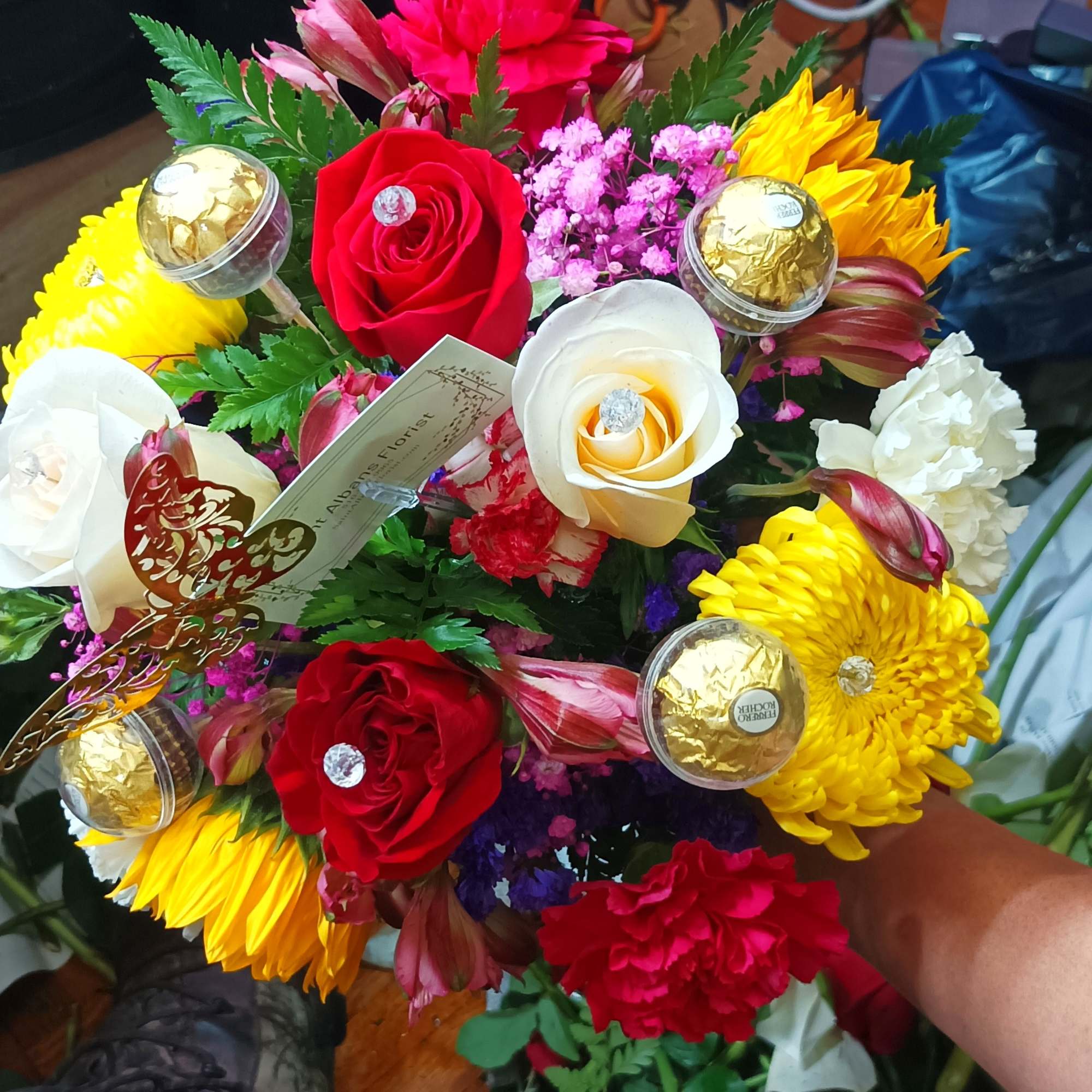 Colorful bouquet with red and white roses, yellow chrysanthemums, and chocolates