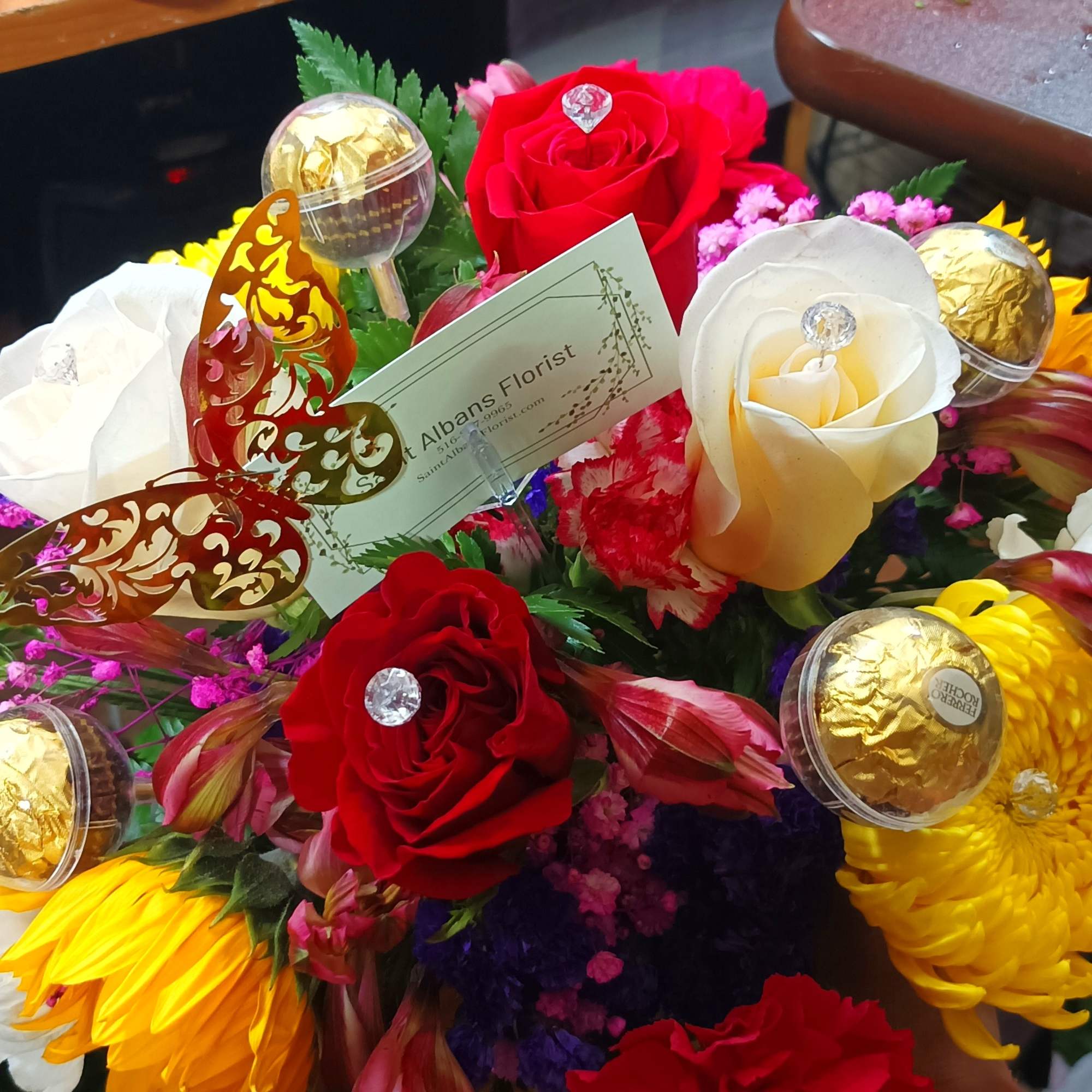 Bouquet of red, white, and yellow roses with chrysanthemums and chocolates