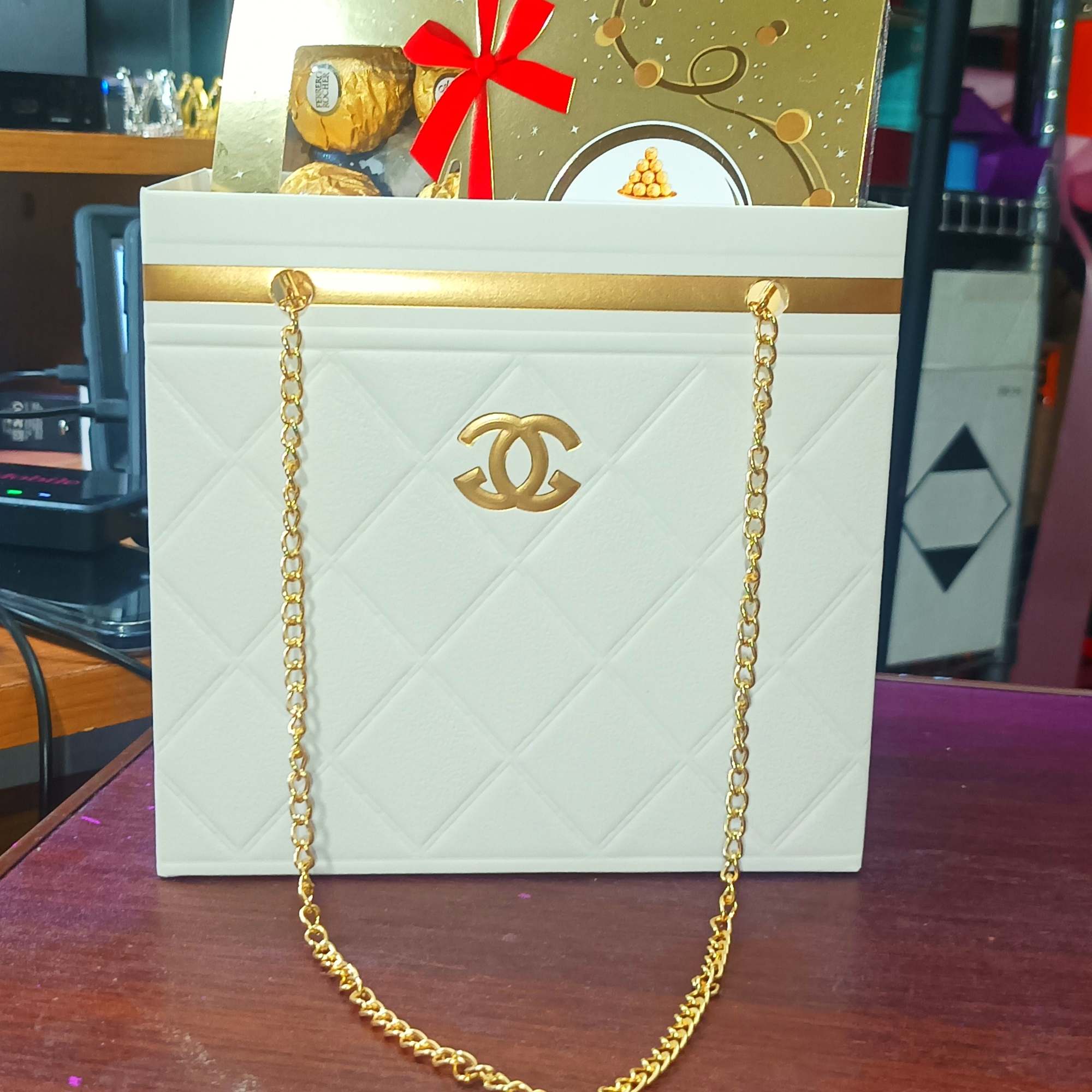 White gift bag with gold chain handles and a gold gift box inside