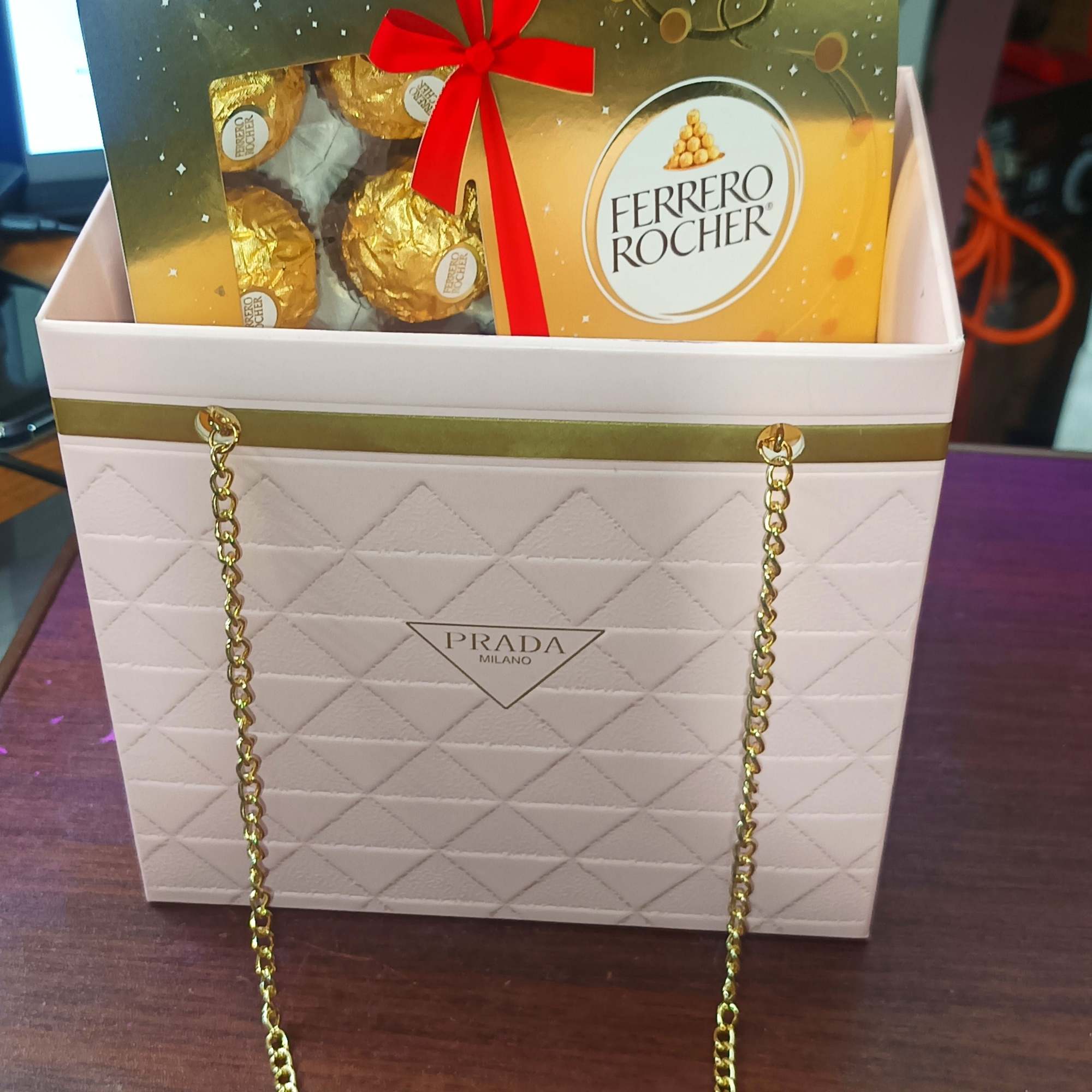 Ferrero Rocher chocolates in a Prada-branded gift bag with a gold chain handle