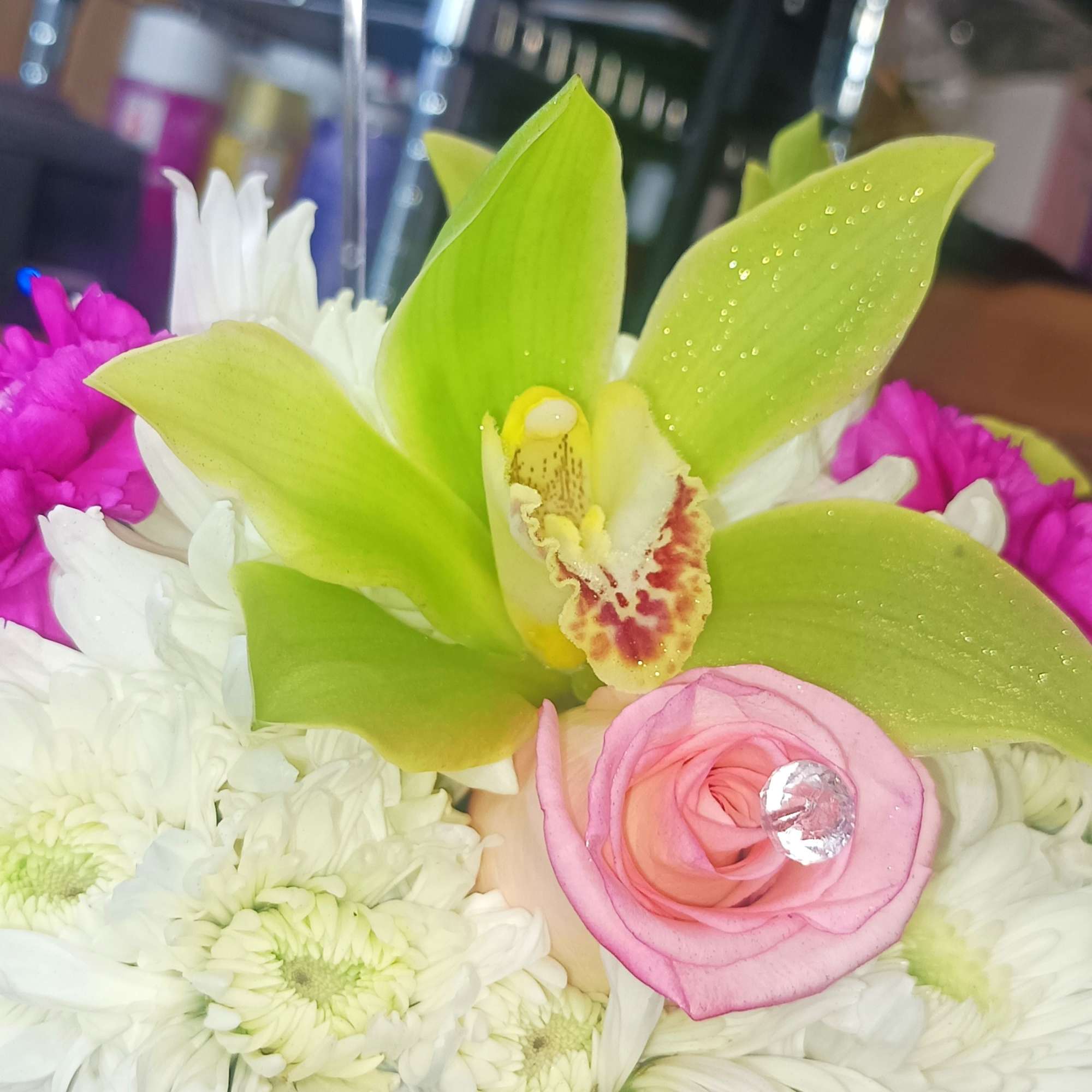 Pink rose and green orchid in a white chrysanthemum arrangement