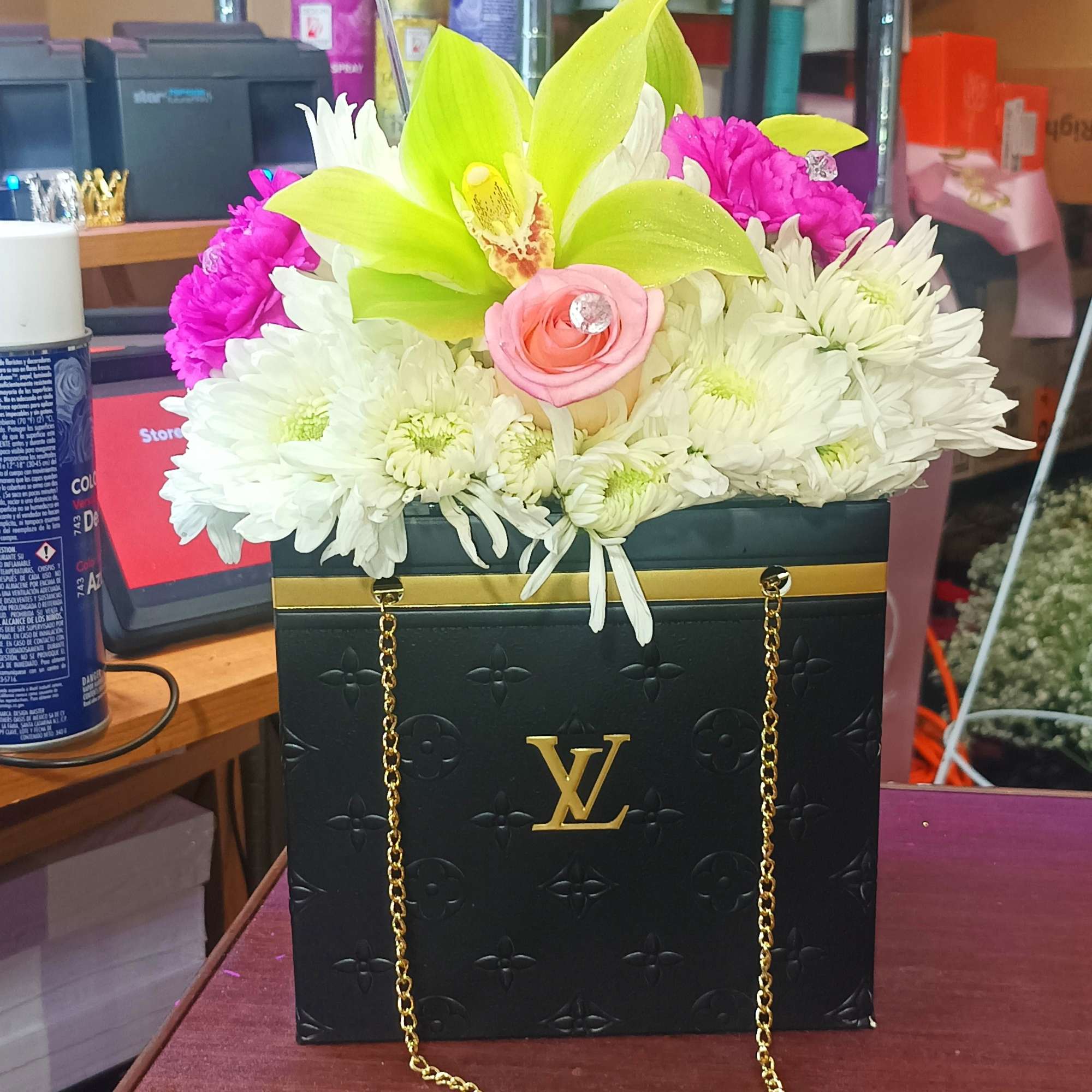Flower arrangement in a black gift box with gold chain and butterfly topper