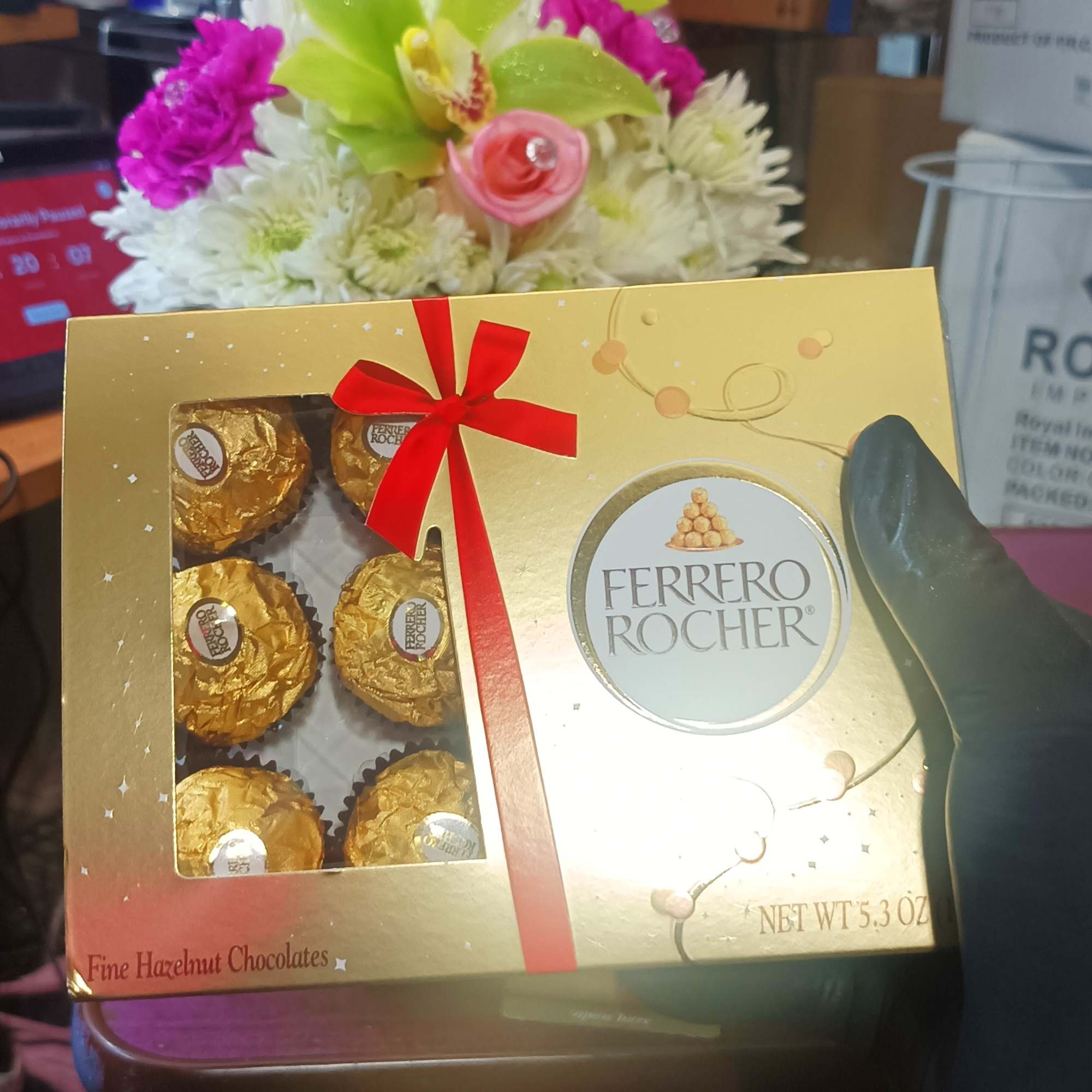 Ferrero Rocher chocolate box held in front of a small flower arrangement