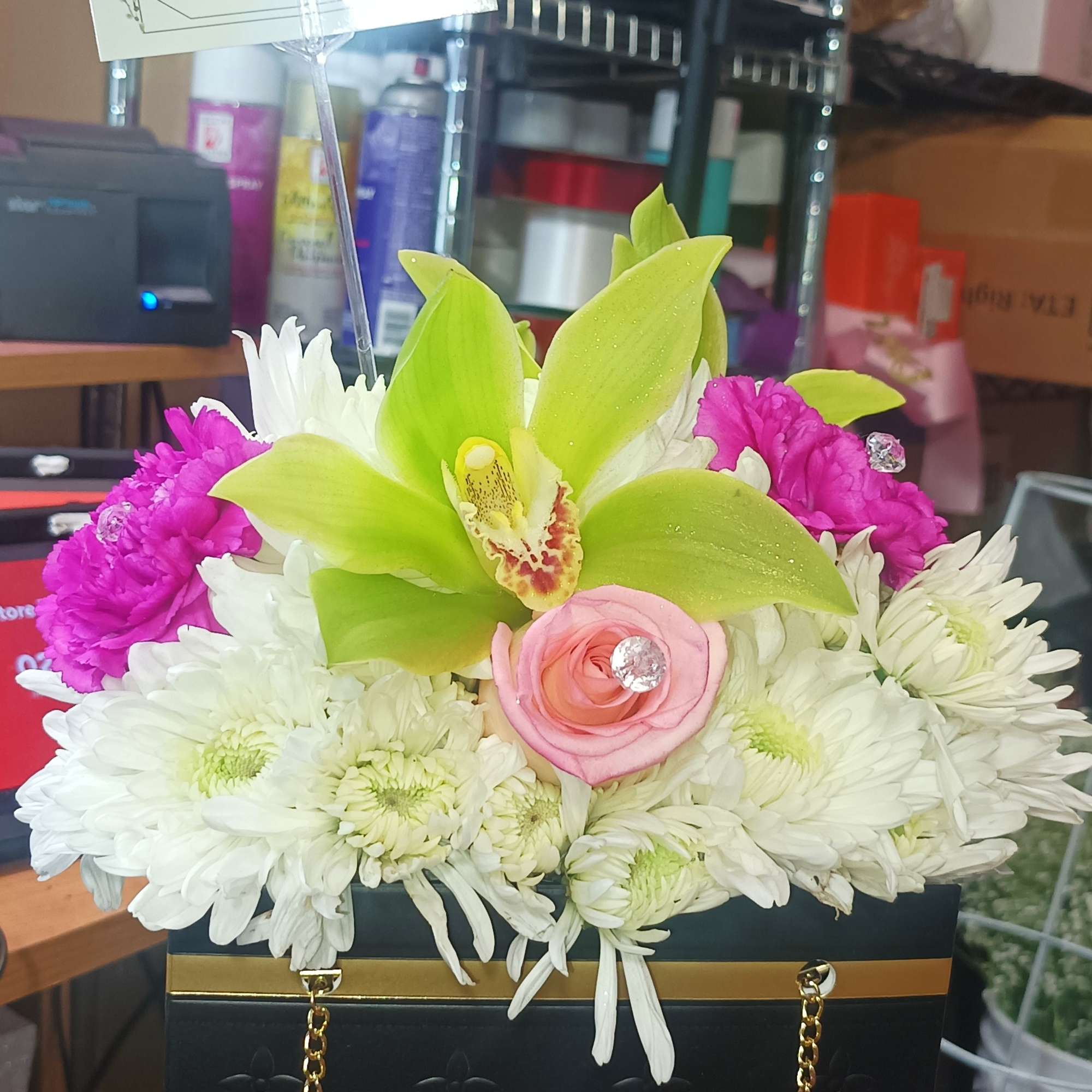 Flower arrangement in a black gift box with a gold butterfly topper