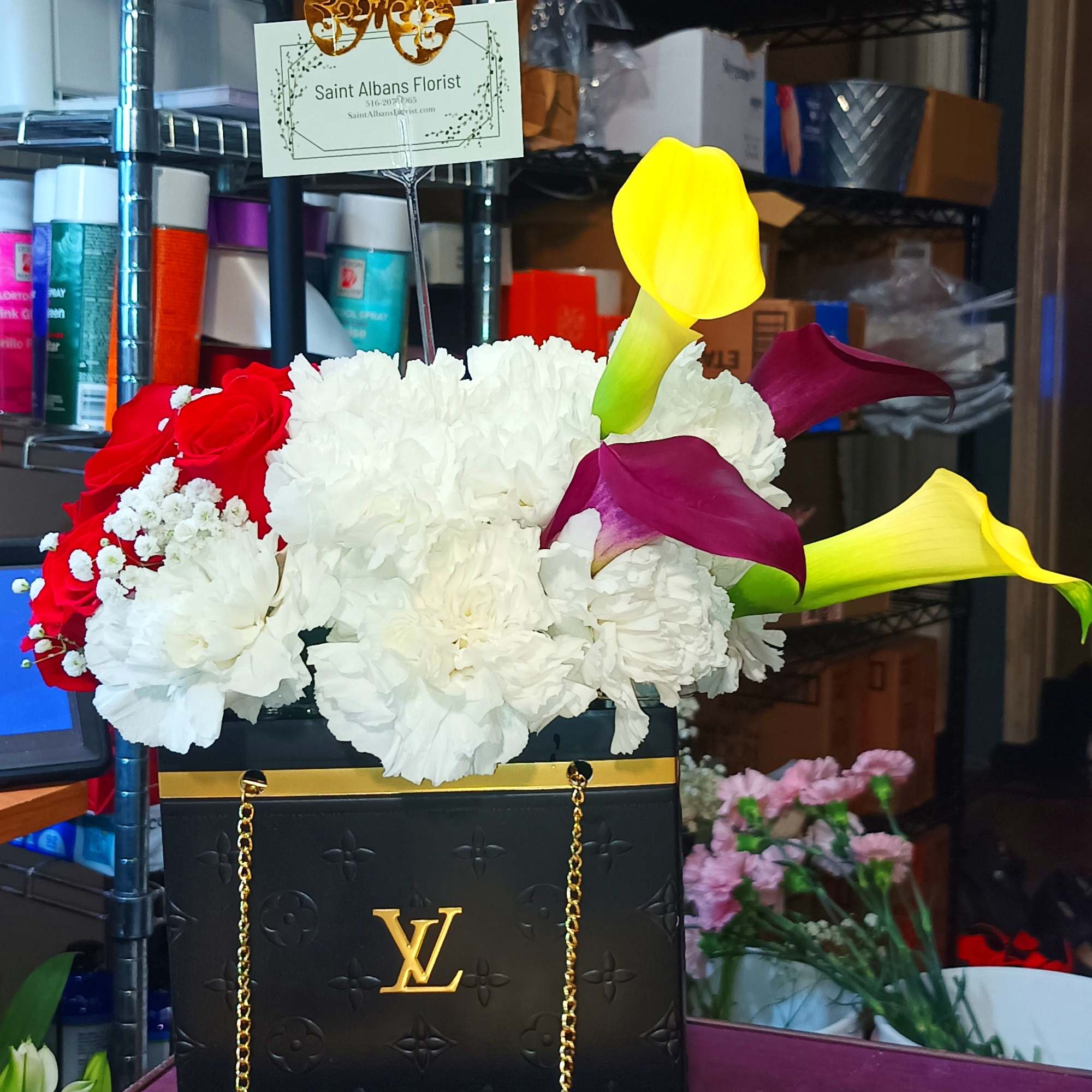 Flower arrangement in a black gift bag with calla lilies and roses, plus a chocolate box