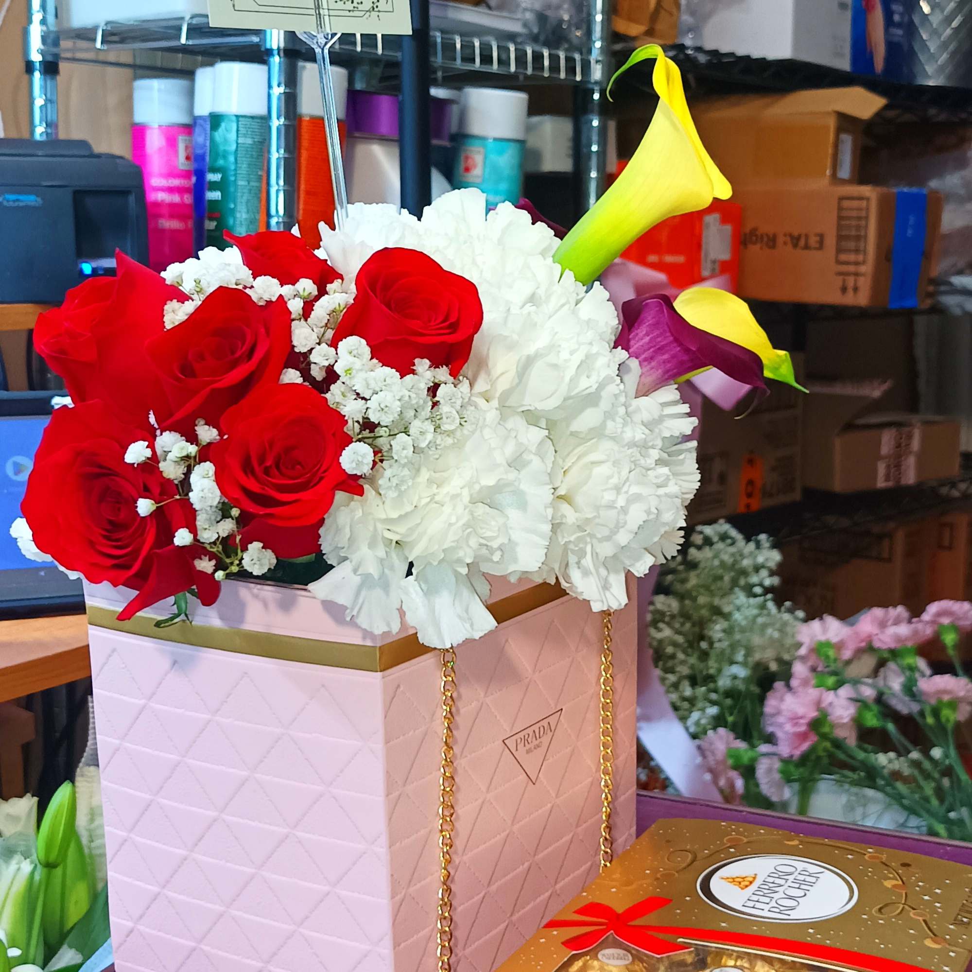 Red roses and white carnations in a pink box with calla lilies