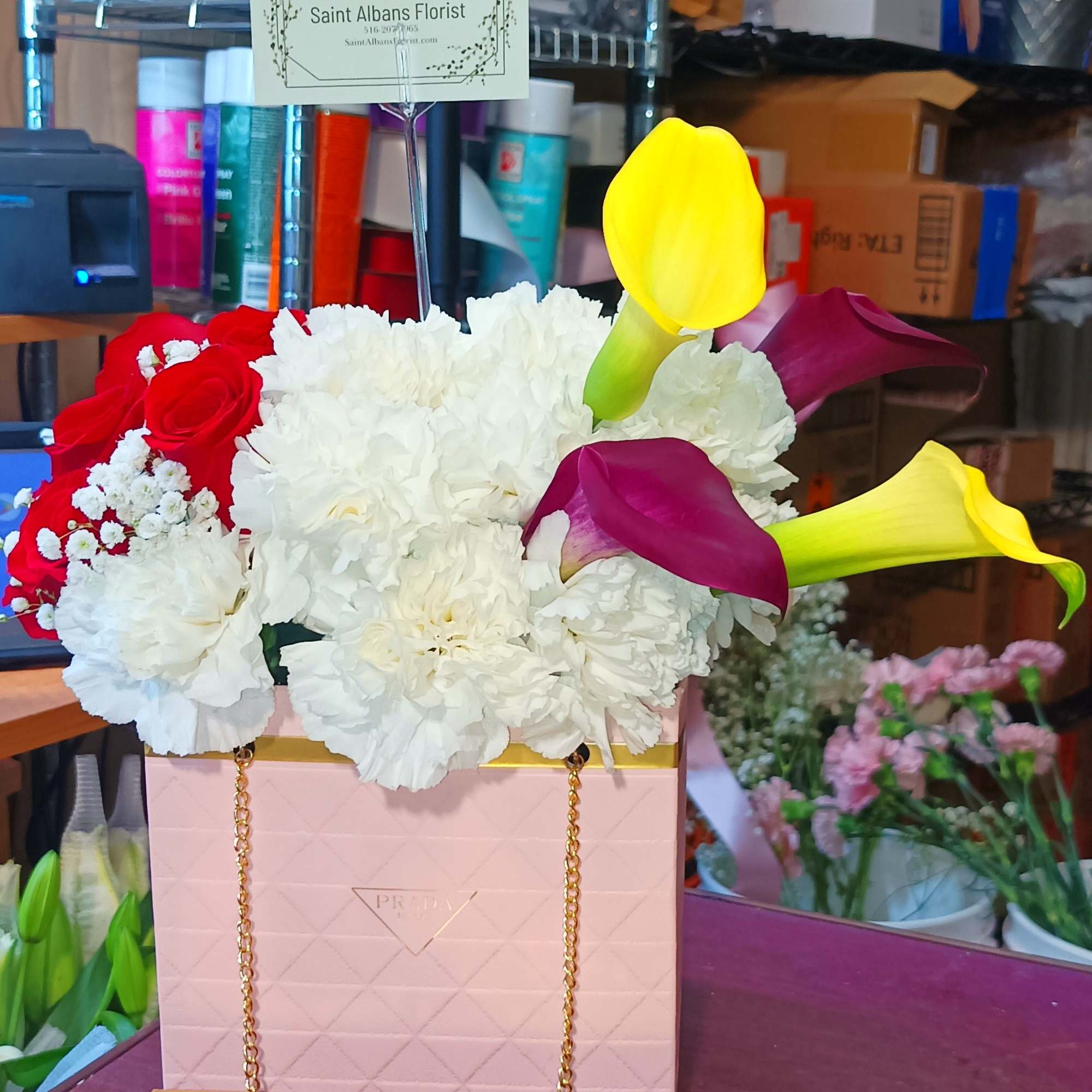 Flower arrangement in a pink gift bag with calla lilies and chocolates