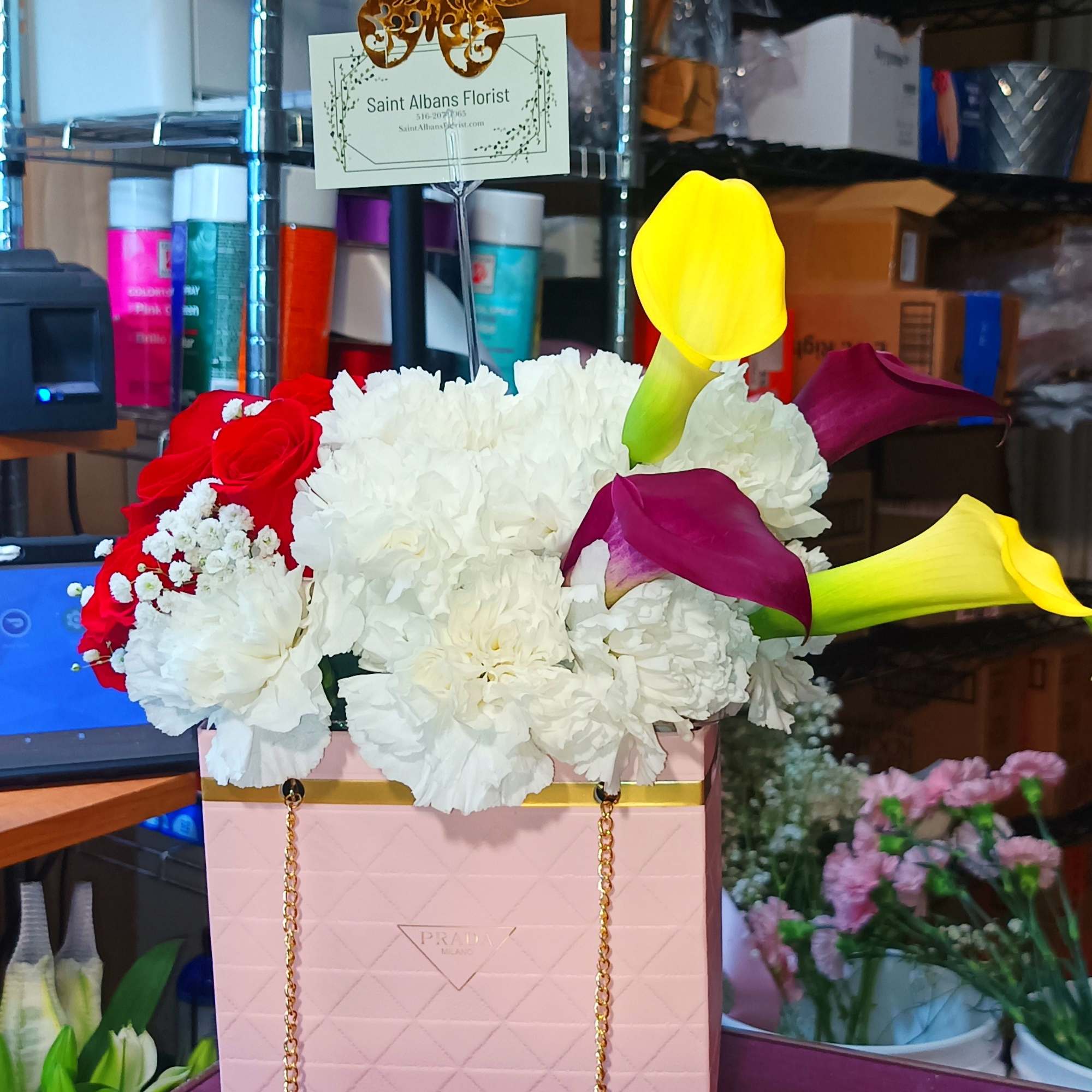 Pink gift bag with white flowers, calla lilies, and chocolates