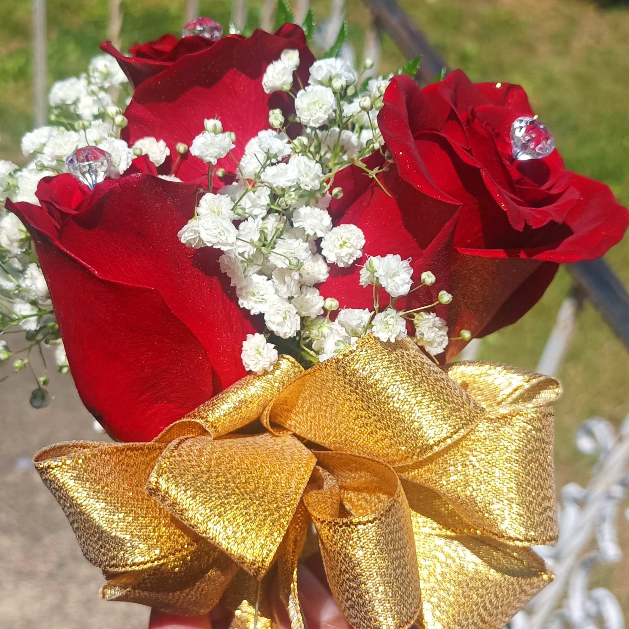 Small bouquet of red roses with white baby's breath and a gold ribbon
