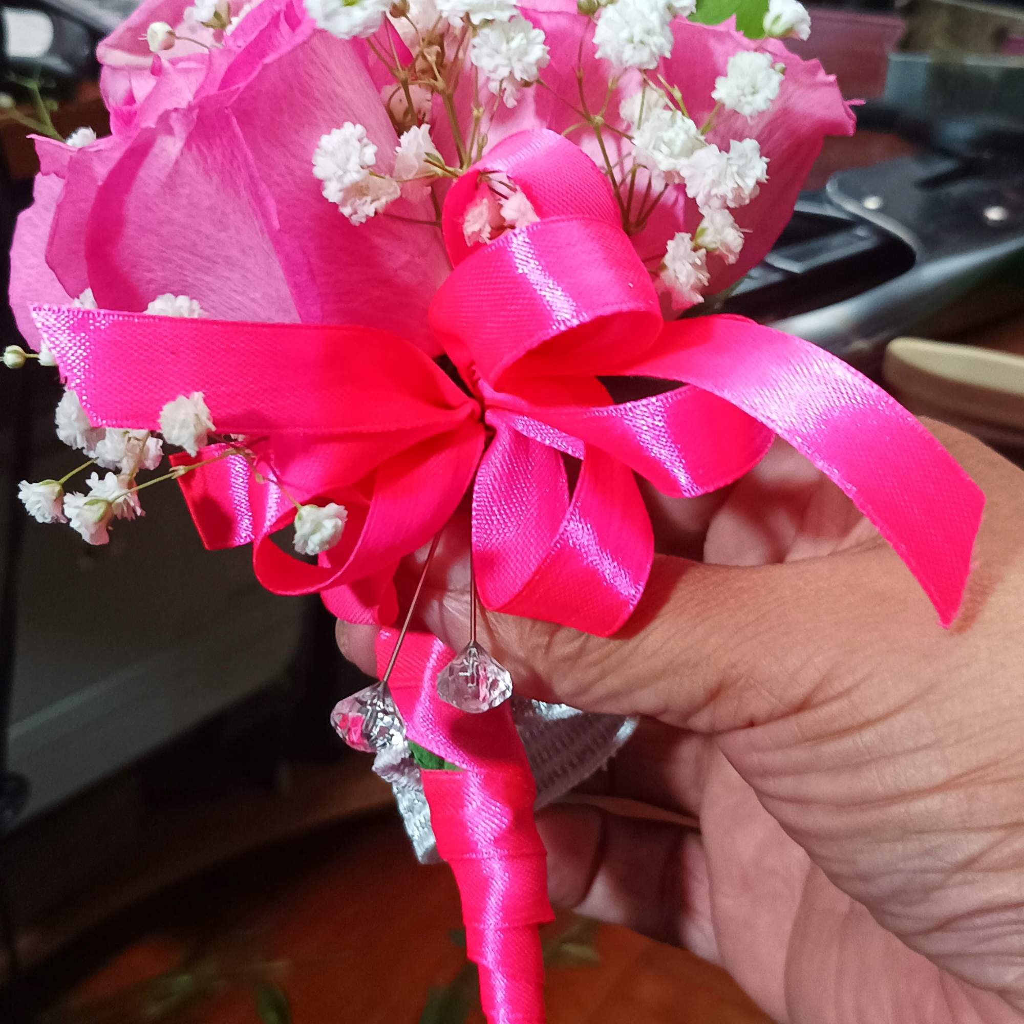 Pink rose boutonniere with baby's breath and a bright ribbon