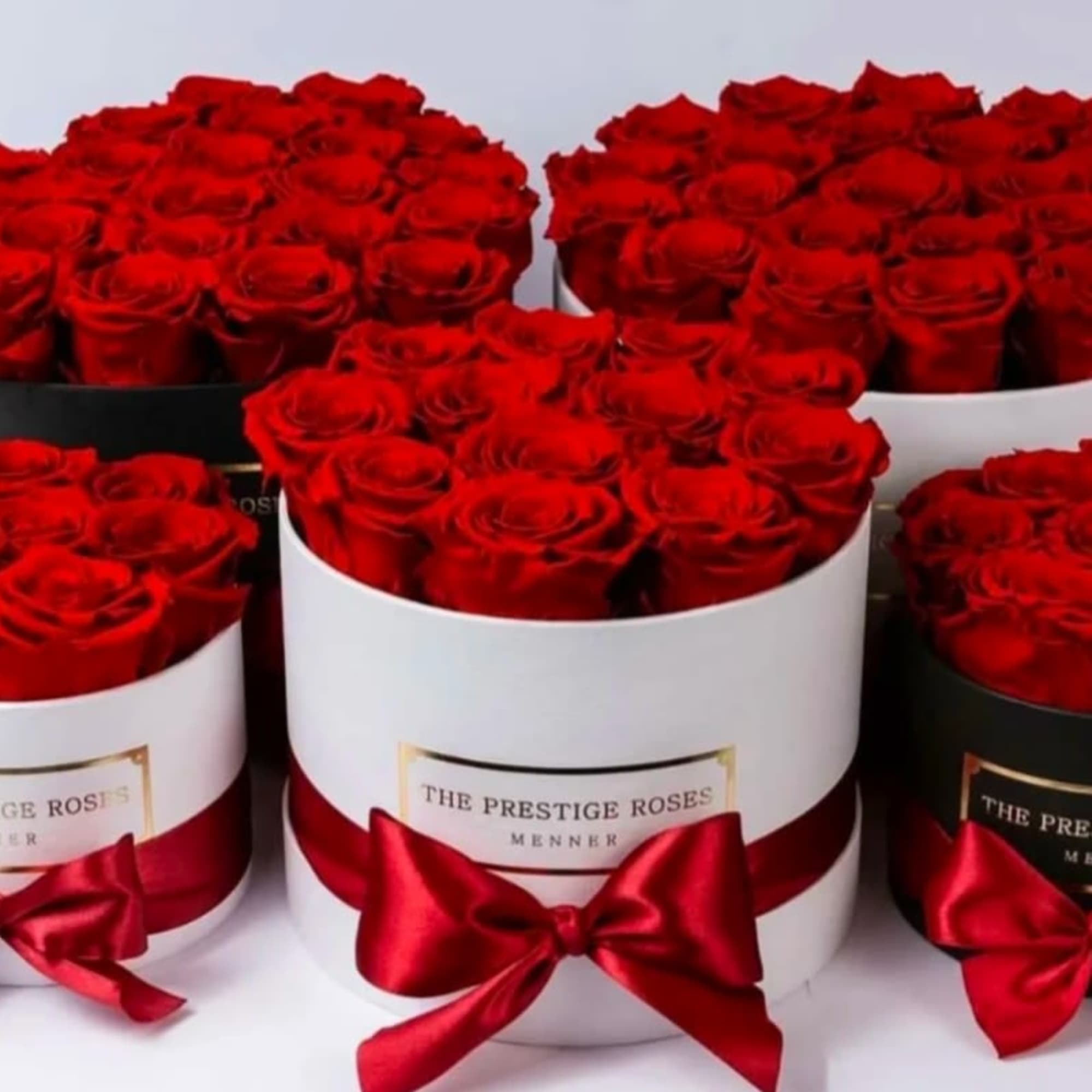Red roses arranged in round hat boxes with satin bows