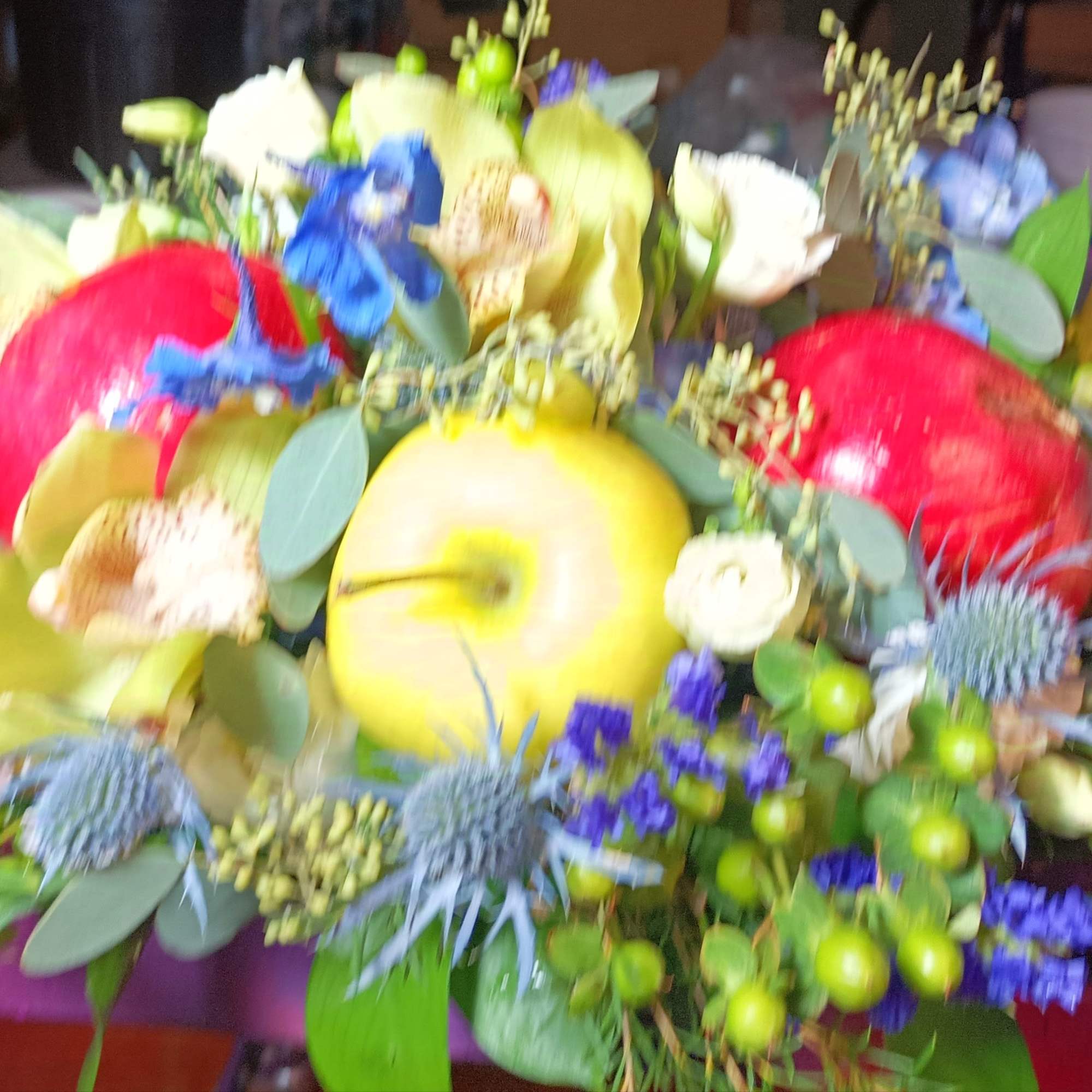 Colorful floral arrangement with apples and mixed blooms on a table