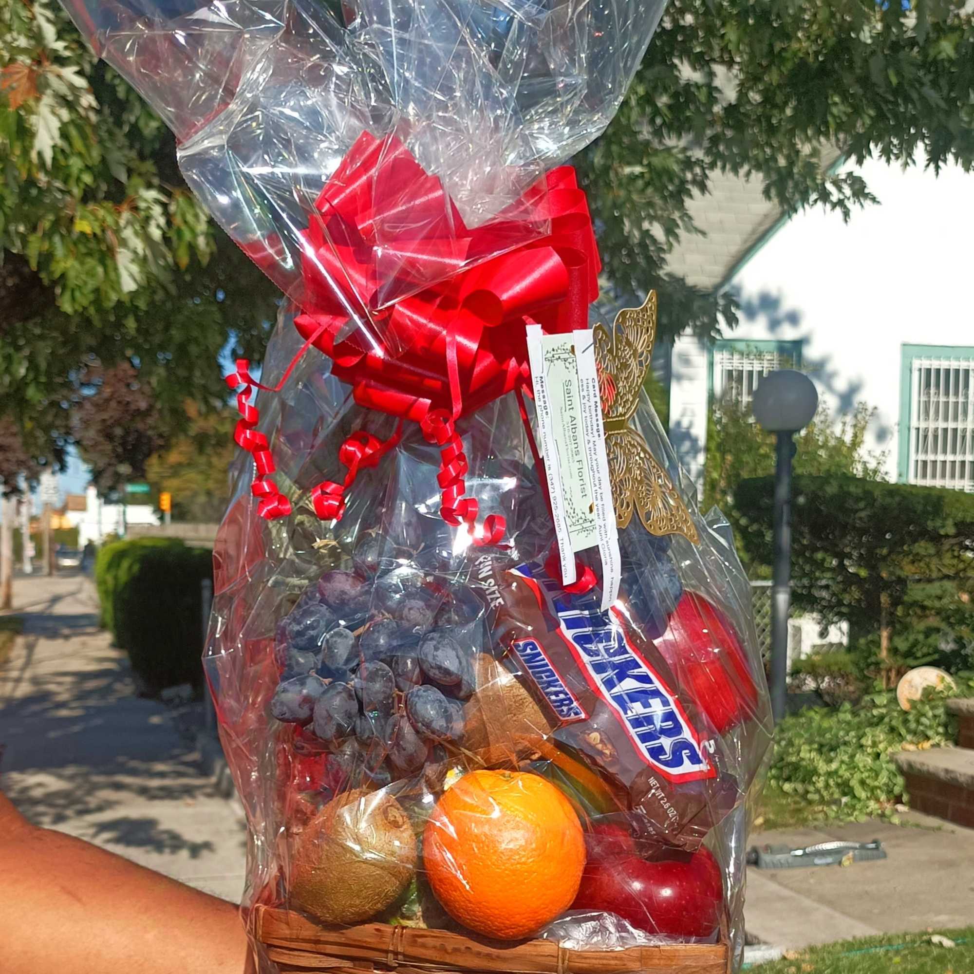 Gift basket with fruit and candy wrapped in clear cellophane and a red bow, photo 3 of 4