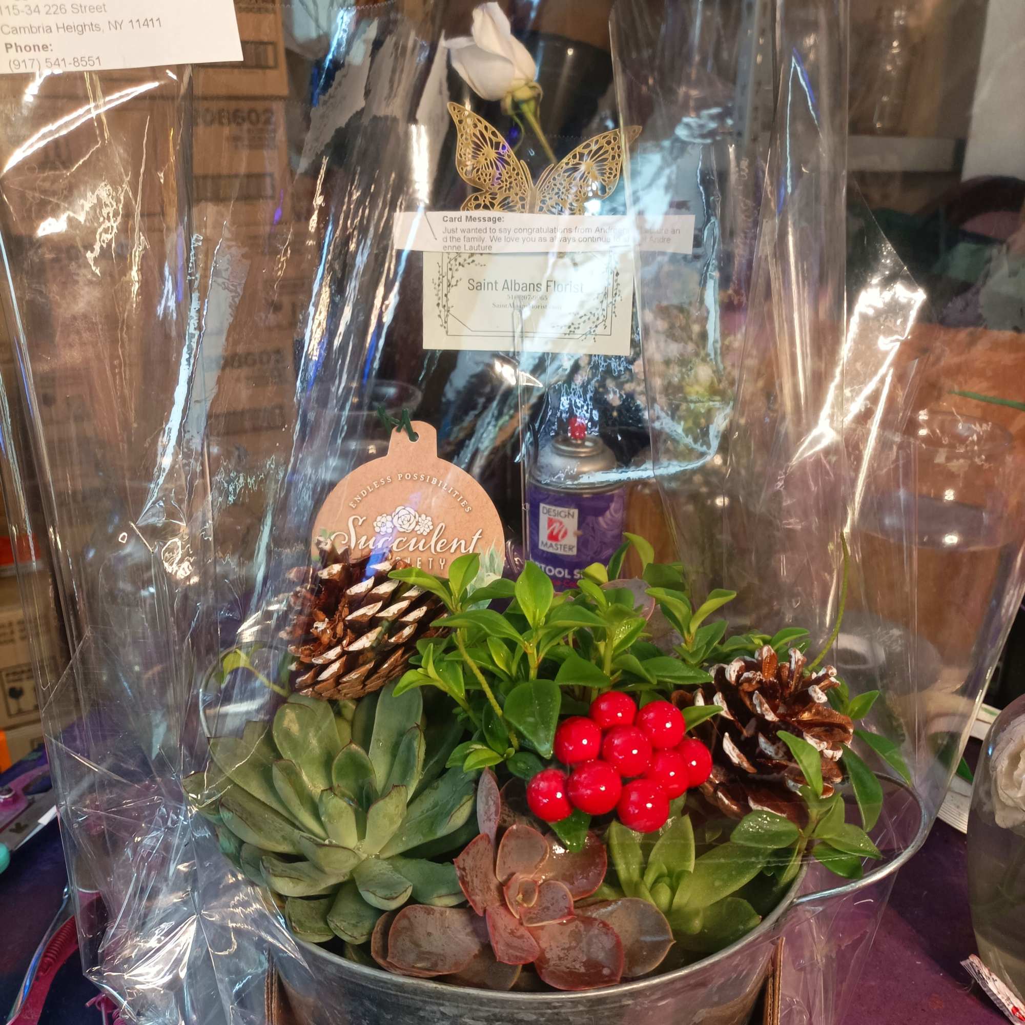Succulent arrangement in a metal container with pinecones and red berries
