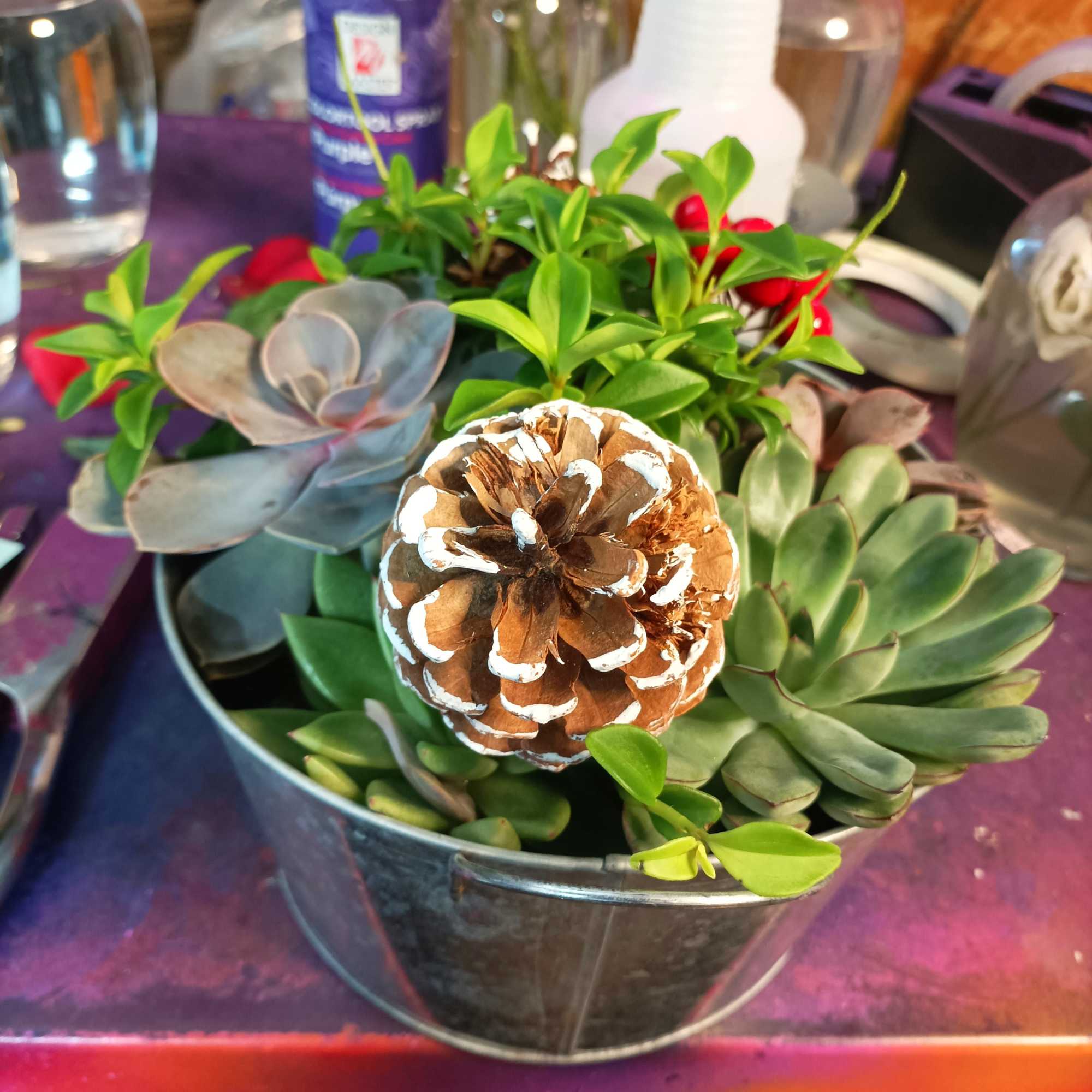 Succulent arrangement in a metal bucket with a painted pinecone centerpiece