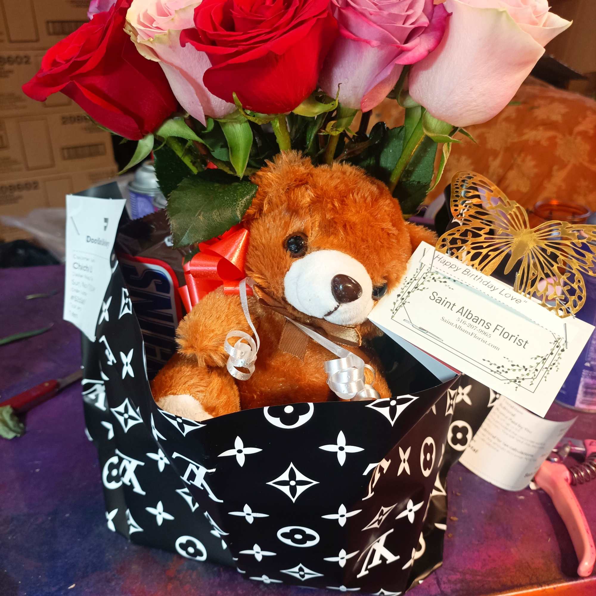 Bouquet of red, pink, and lavender roses with a teddy bear in a gift wrap