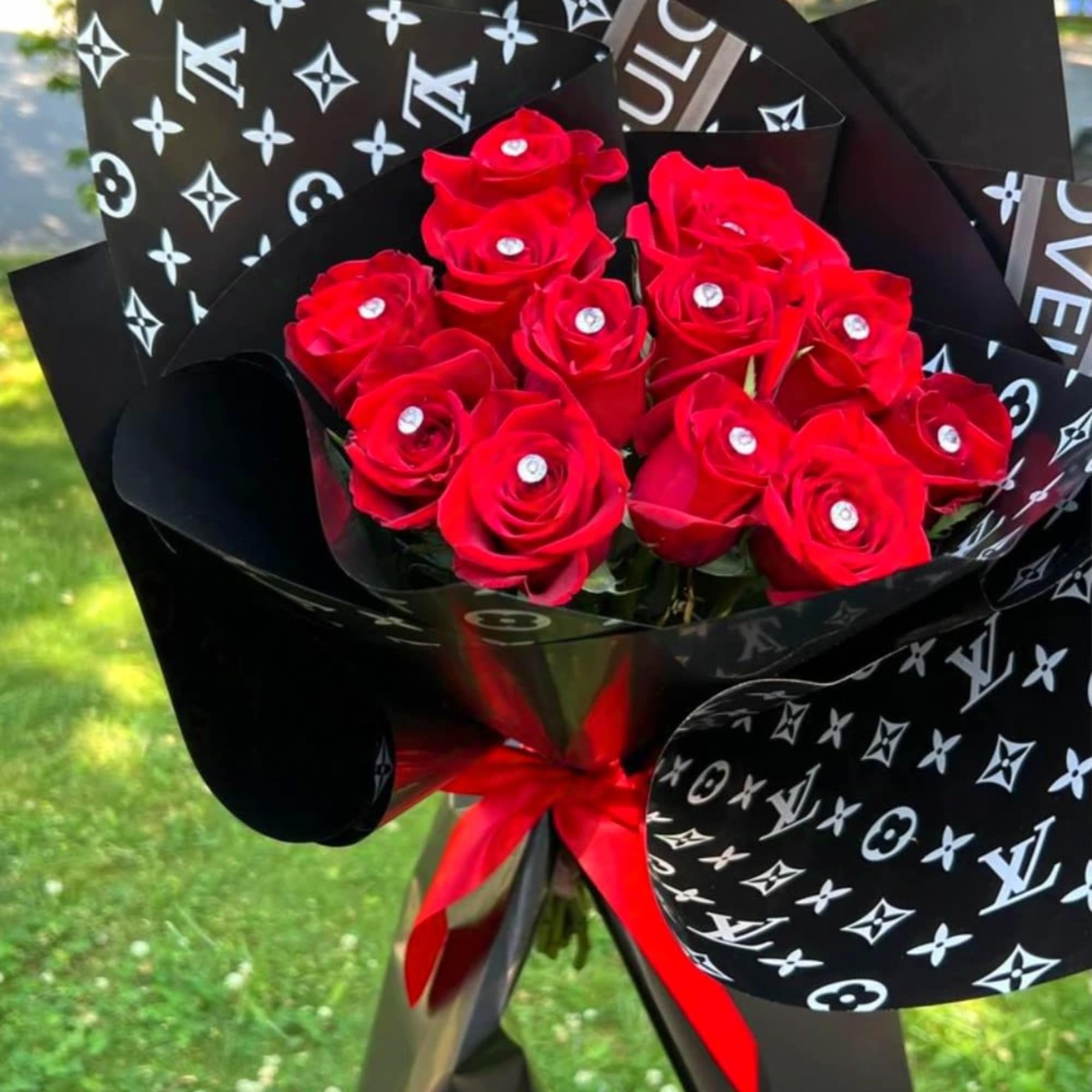 Bouquet of red roses wrapped in black patterned paper with a red ribbon
