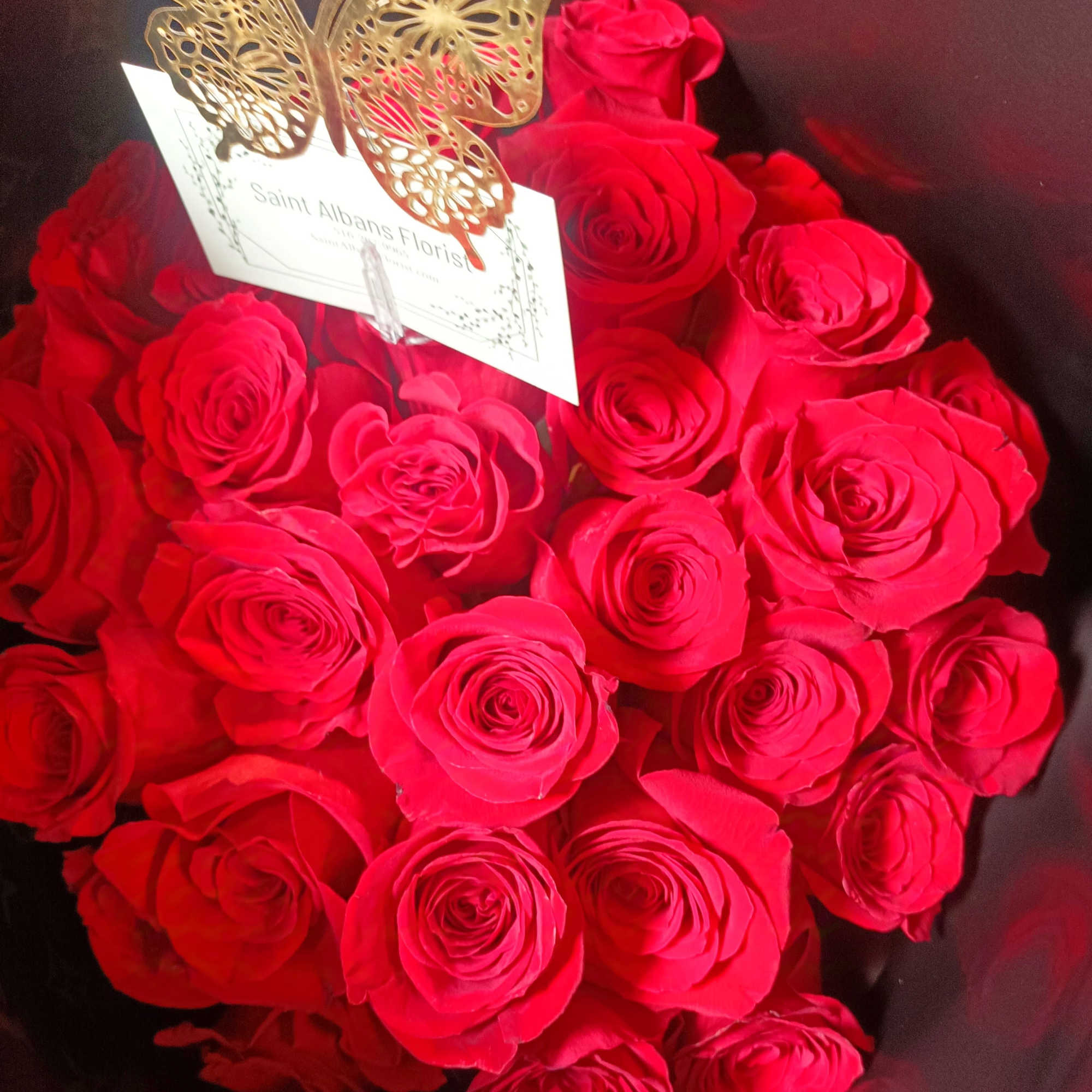 Bouquet of red roses with a gold butterfly decoration and card