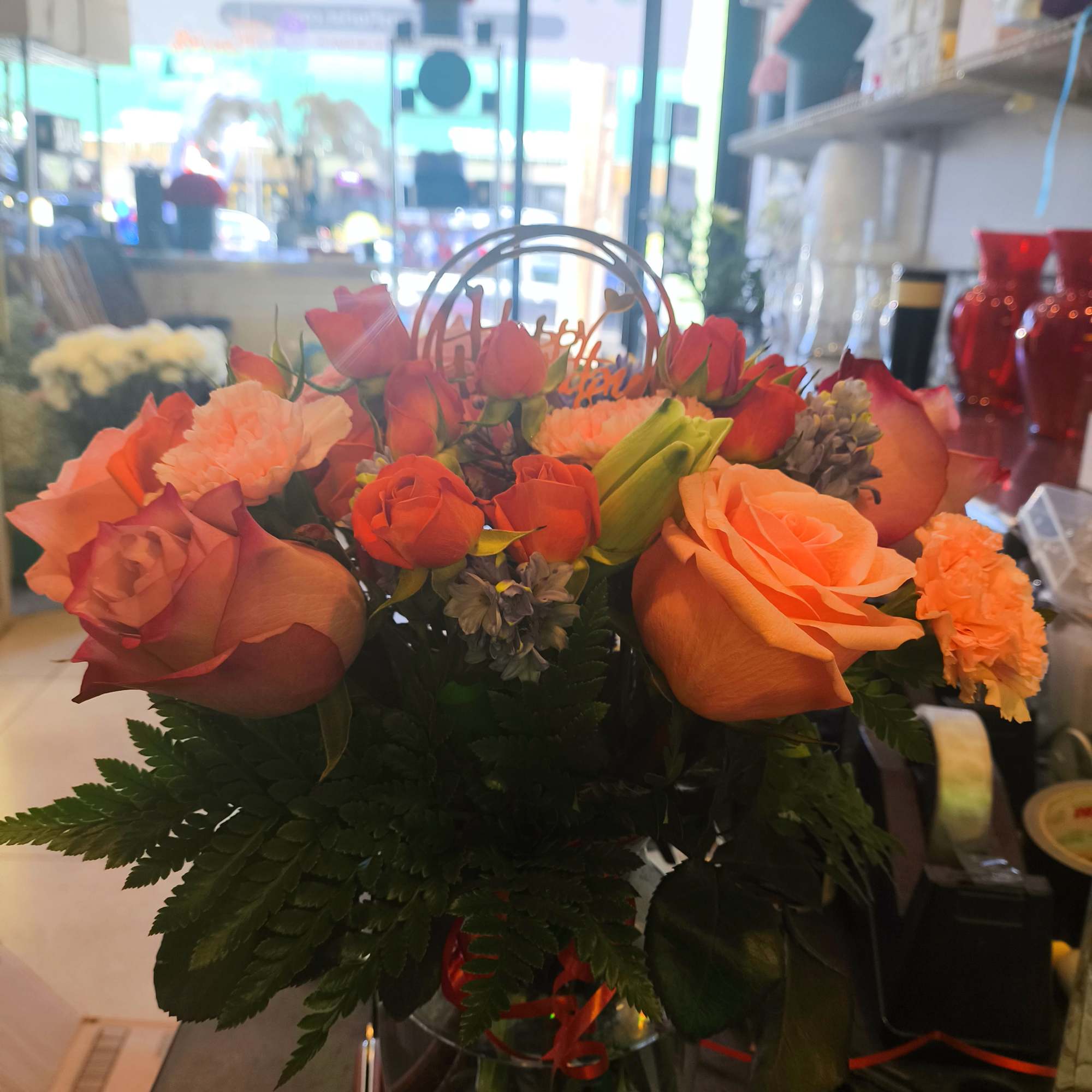 Orange and pink rose bouquet in a glass vase